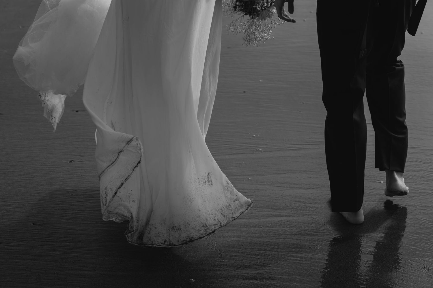A couple in formal wedding attire dances together on a dark dance floor during their reception celebration.