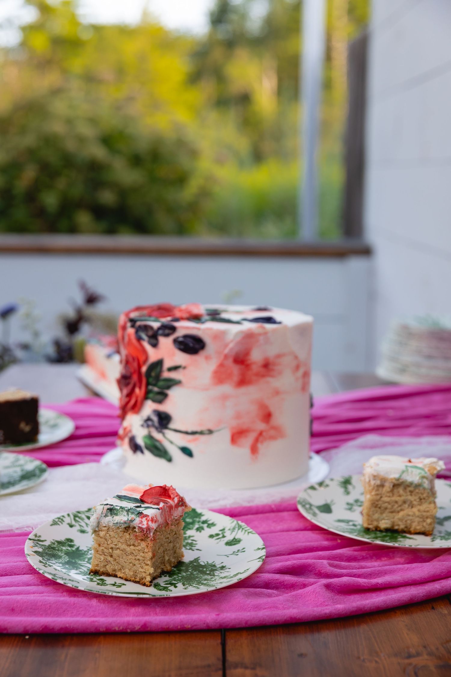 A series of four photos showing slices of a decorated cake with pink frosting and floral designs on patterned plates.