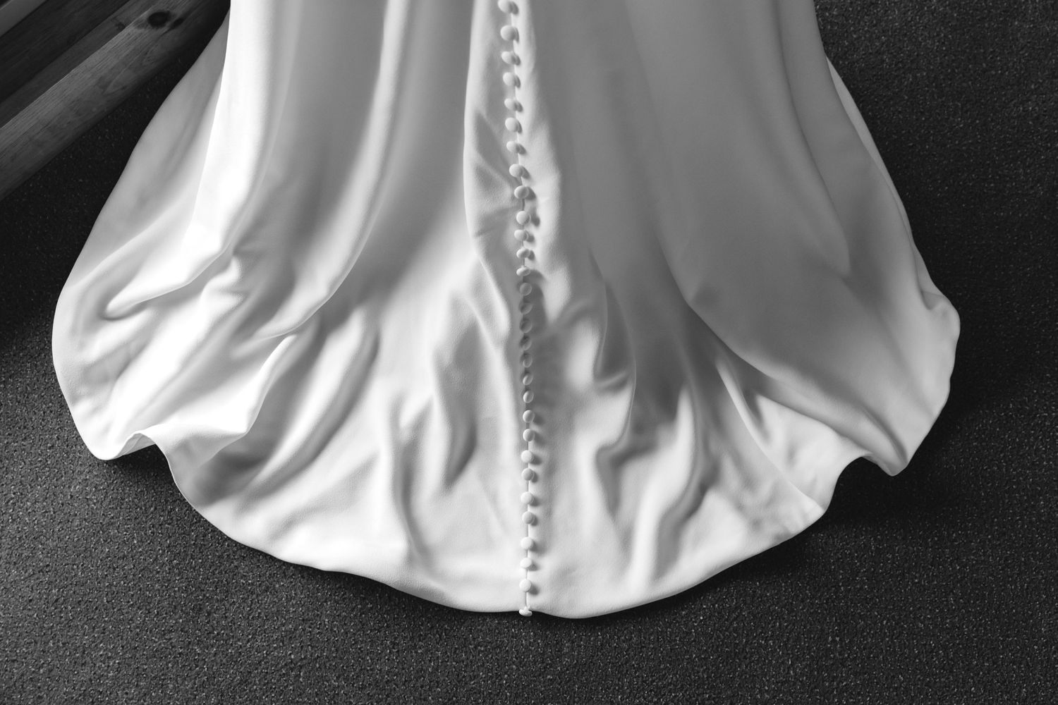 Close-up detail of white wedding dress showing button closures along the back.