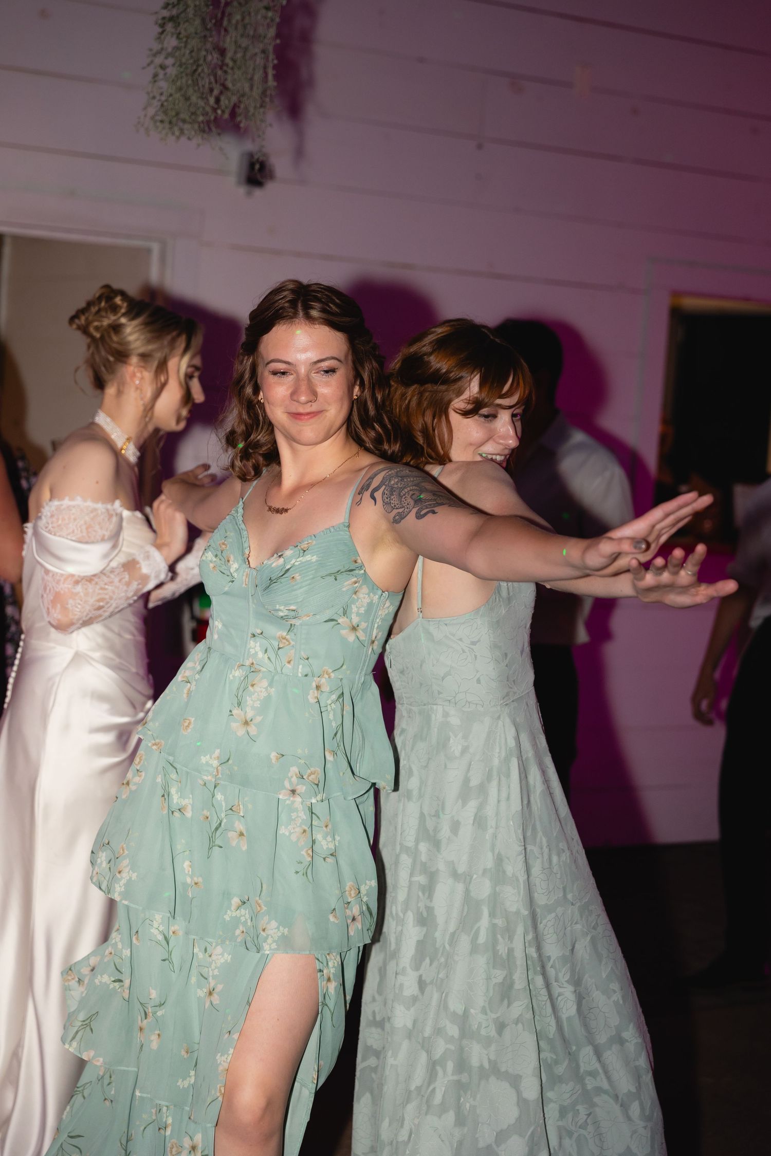 A group of people in mint green dresses dance together in a line at what appears to be a wedding reception.