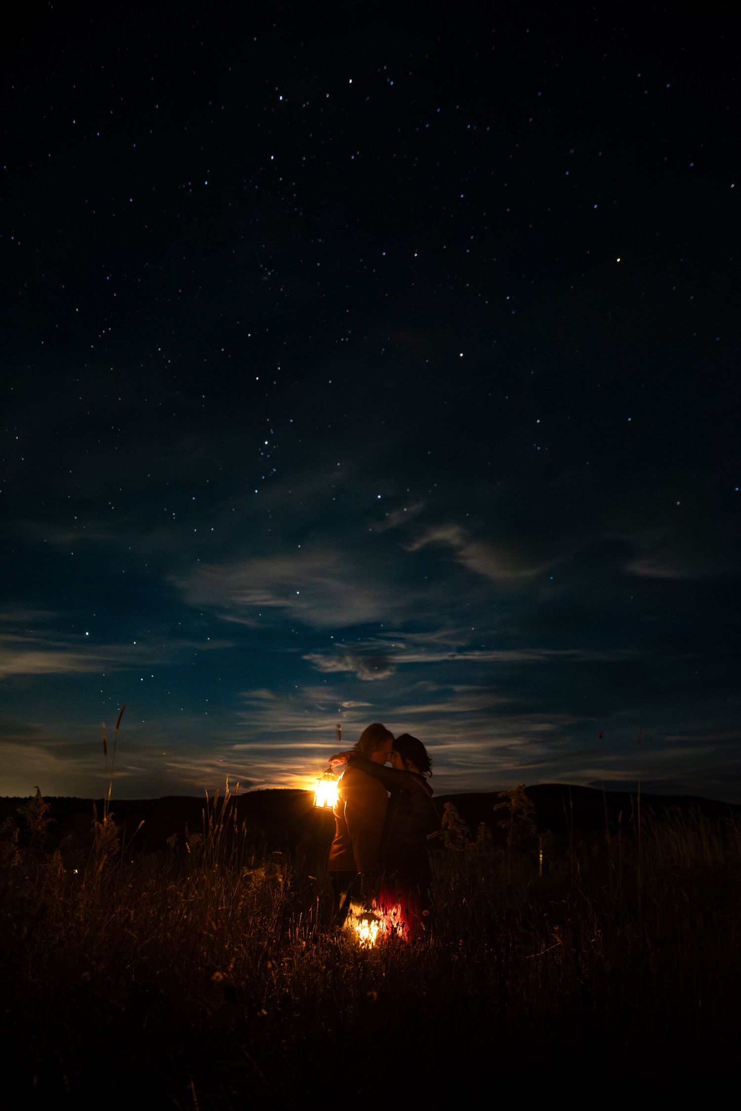 A stunning time-lapse sequence of a starry night sky with a campfire glowing on the horizon at dusk.