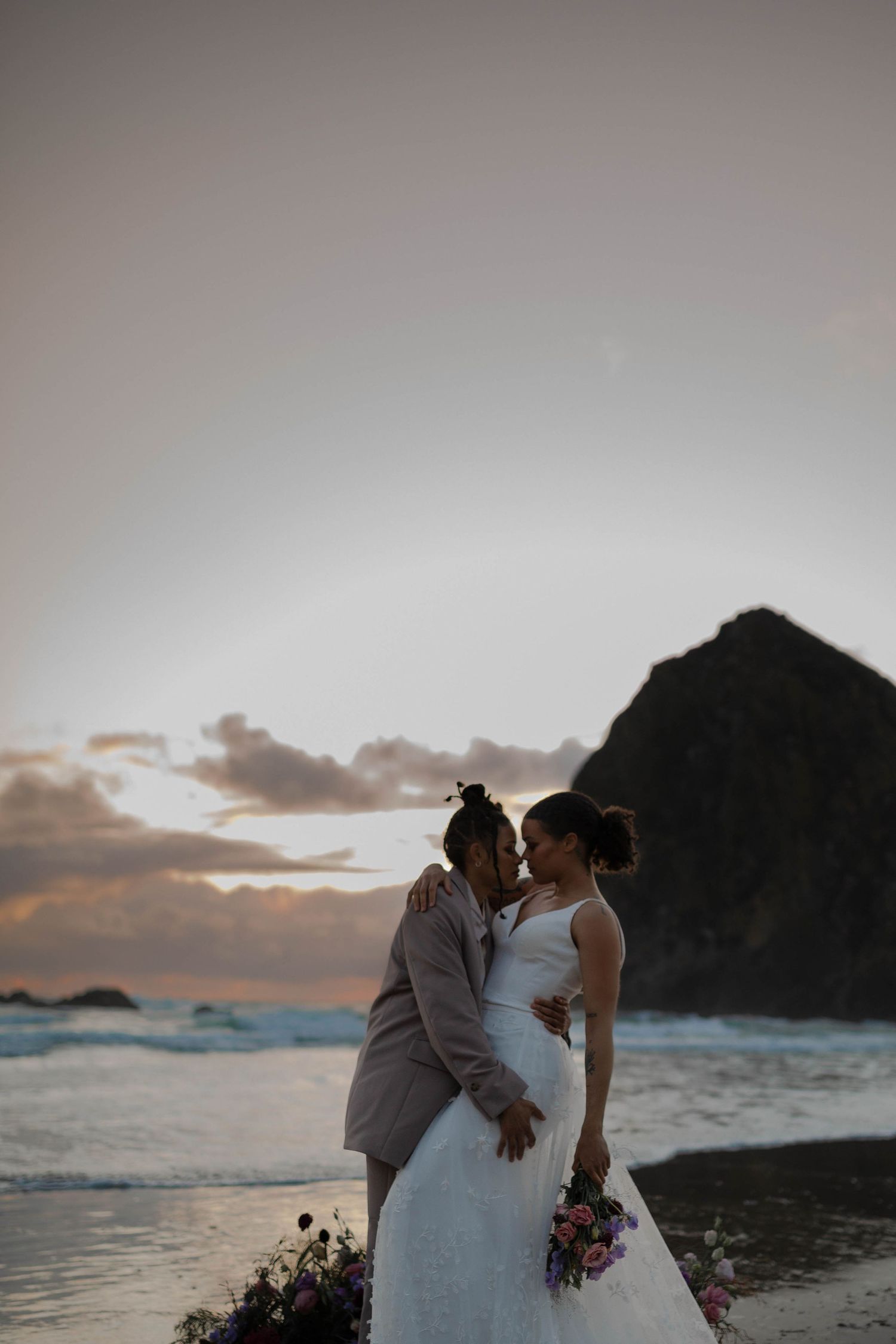 A romantic sunset beach wedding photo with Haystack Rock forming a dramatic backdrop.