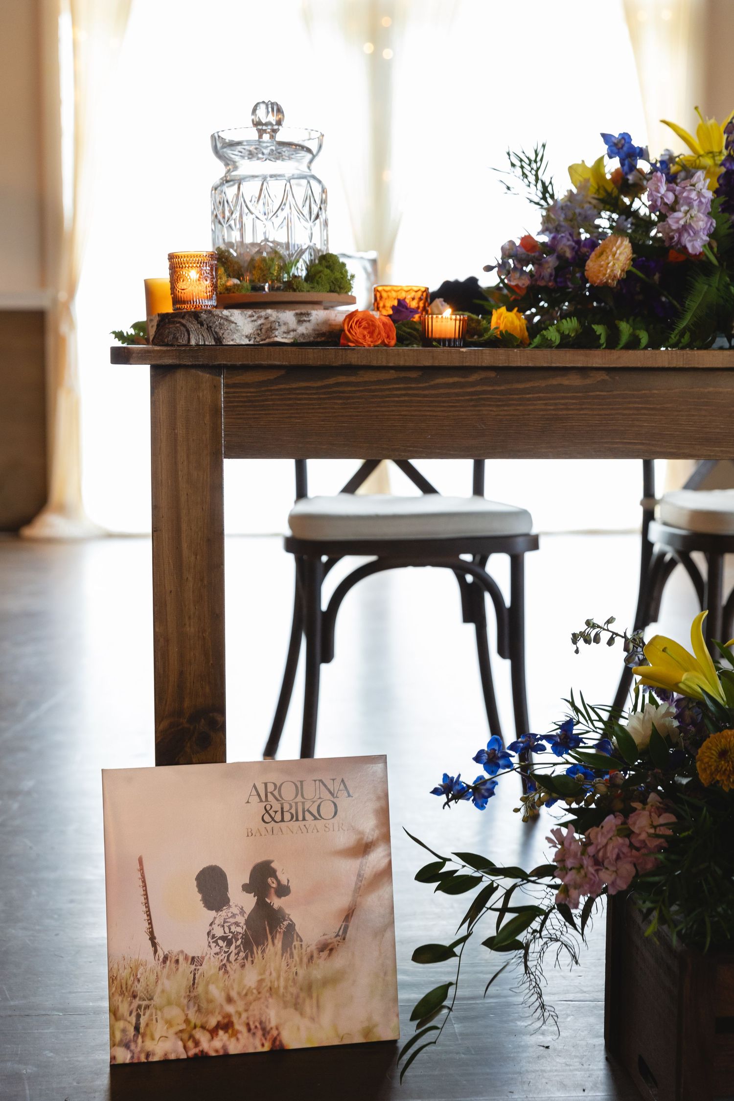 Rustic table setting with glass cloche, flowers and vinyl record displayed at wedding reception.