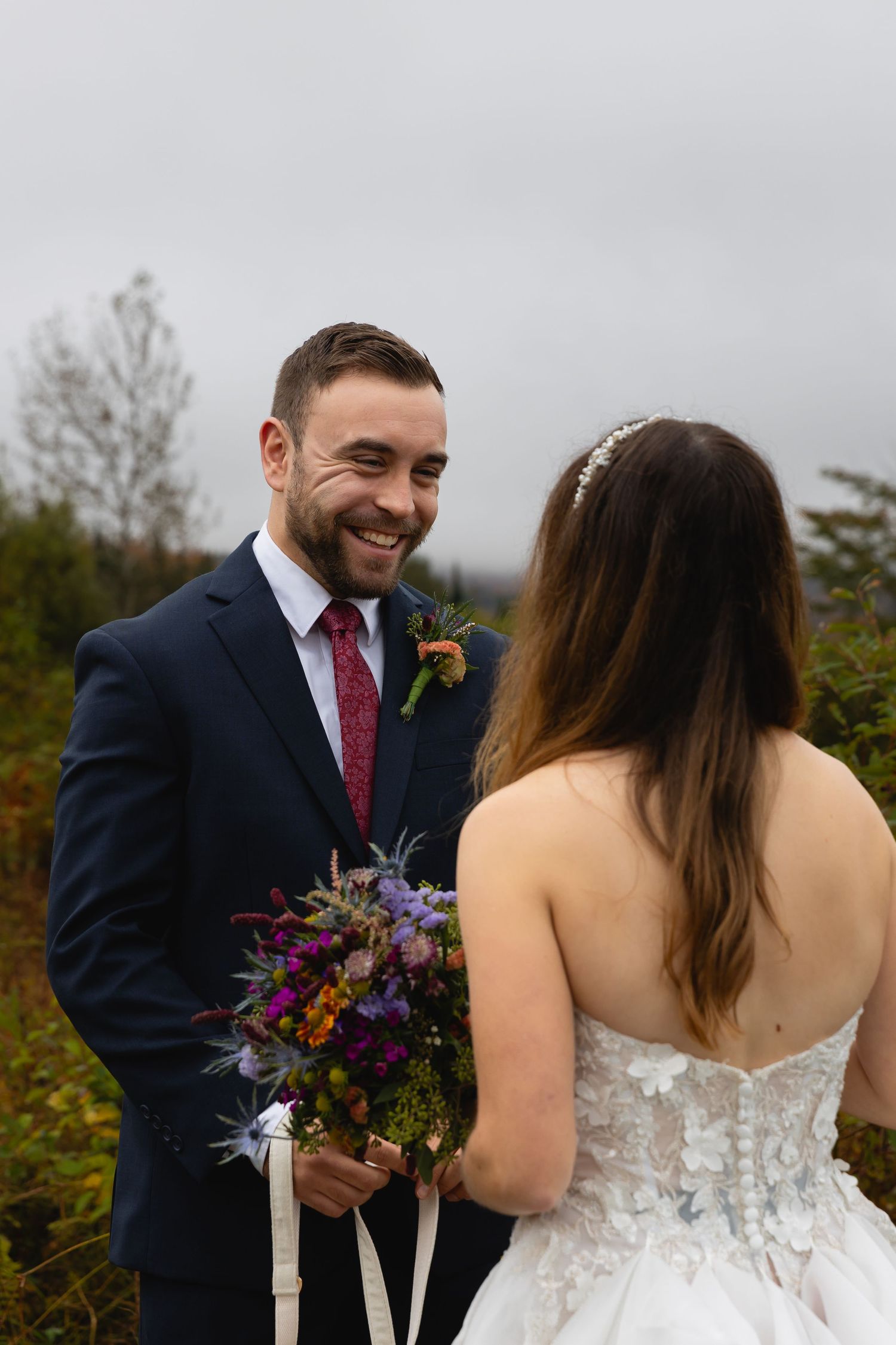 A joyful moment shared during an outdoor mountain wedding ceremony with colorful wildflower bouquet.