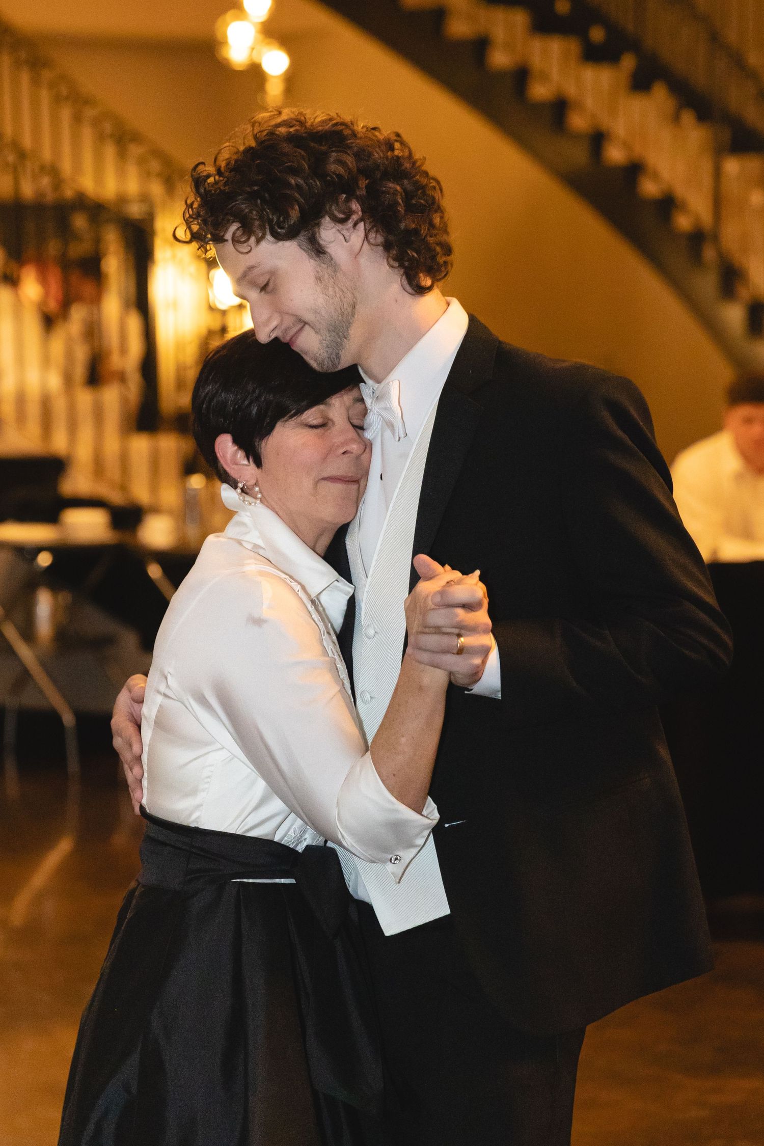 A couple shares an intimate slow dance at an elegant venue with warm lighting and beautiful architectural details.