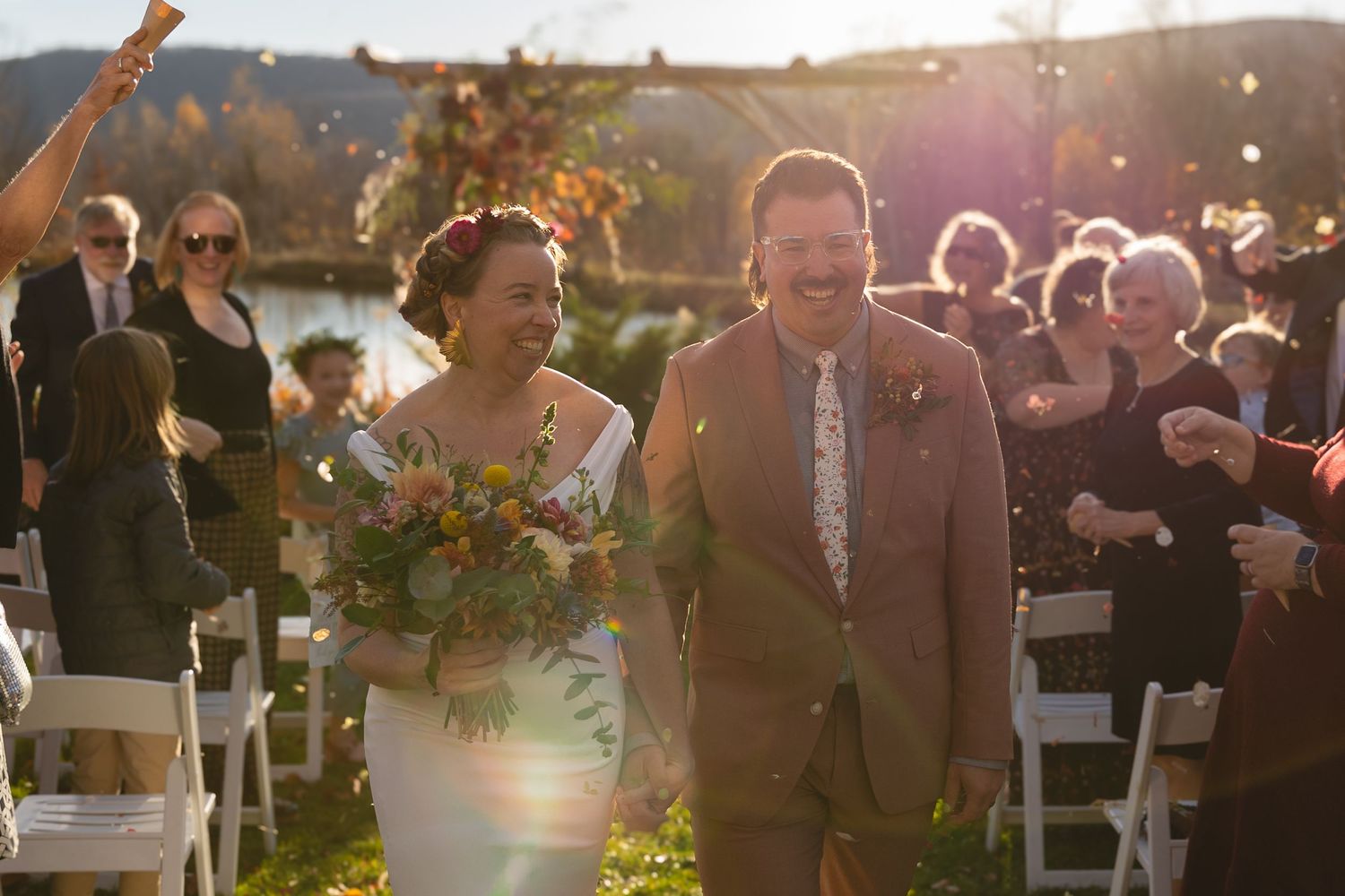 Joyful celebration moment during an outdoor fall wedding with golden sunlight.