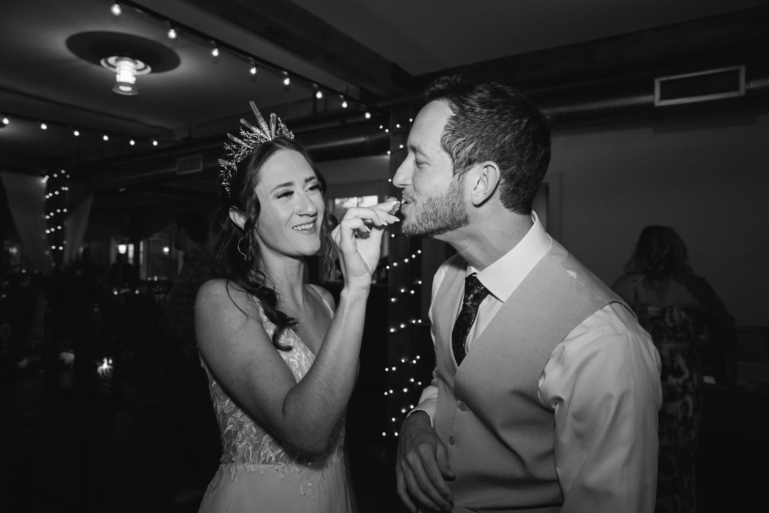 Black and white candid moment of newlyweds during reception festivities.