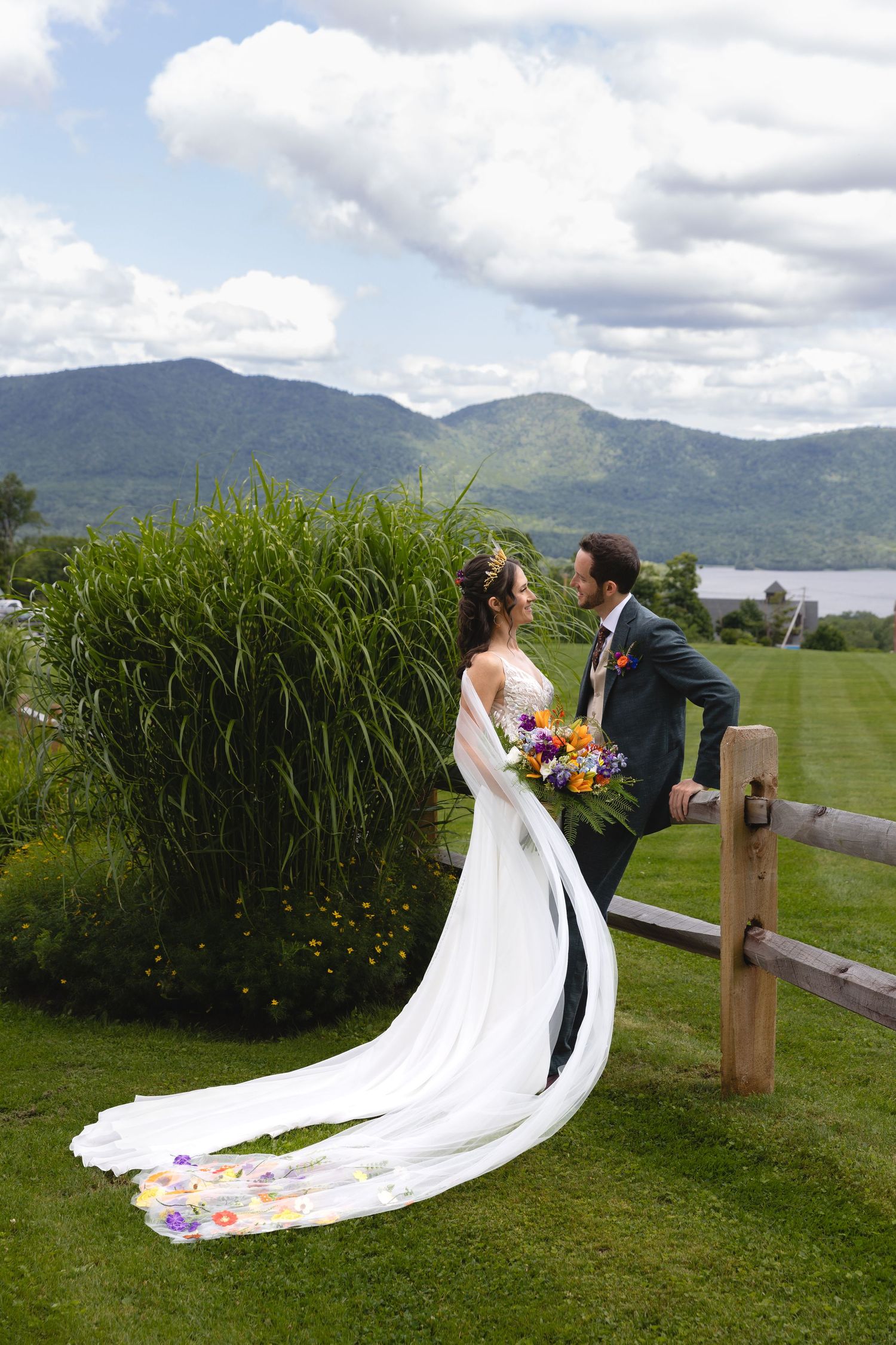 Wedding couple shares a romantic moment on a scenic mountainside with a flowing white dress train.