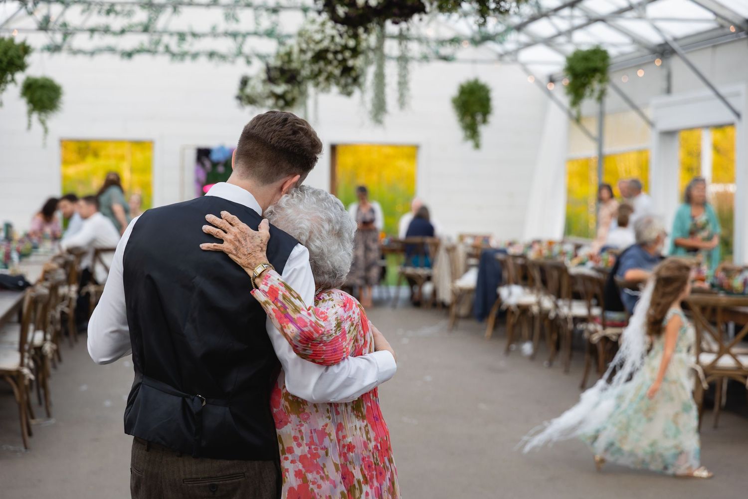 Couples dance together at an elegant ballroom event with decorative lighting and formal attire.