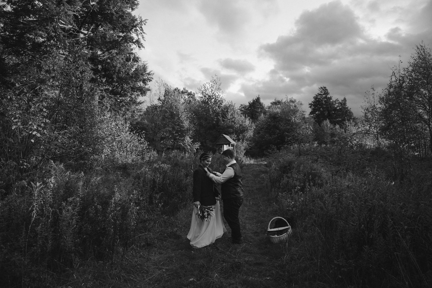 A black and white wedding photo taken in a rustic outdoor field setting.