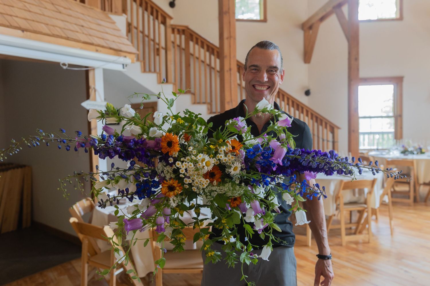 Colorful wildflower arrangement being displayed in rustic wooden interior setting.