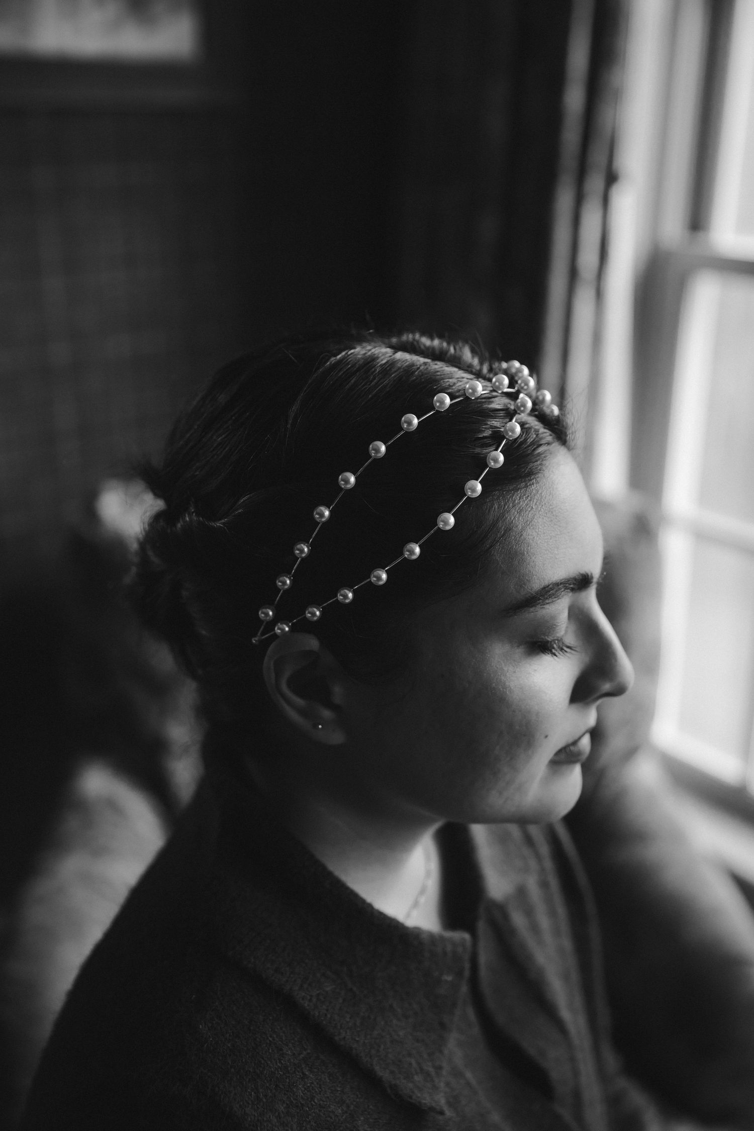 A profile portrait showing an elegant pearl hair accessory in black and white.