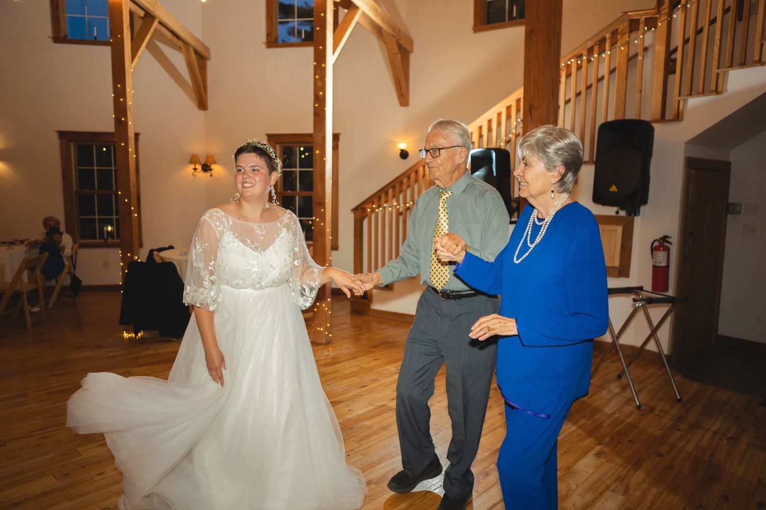Wedding celebration on wooden dance floor with guests in formal attire.