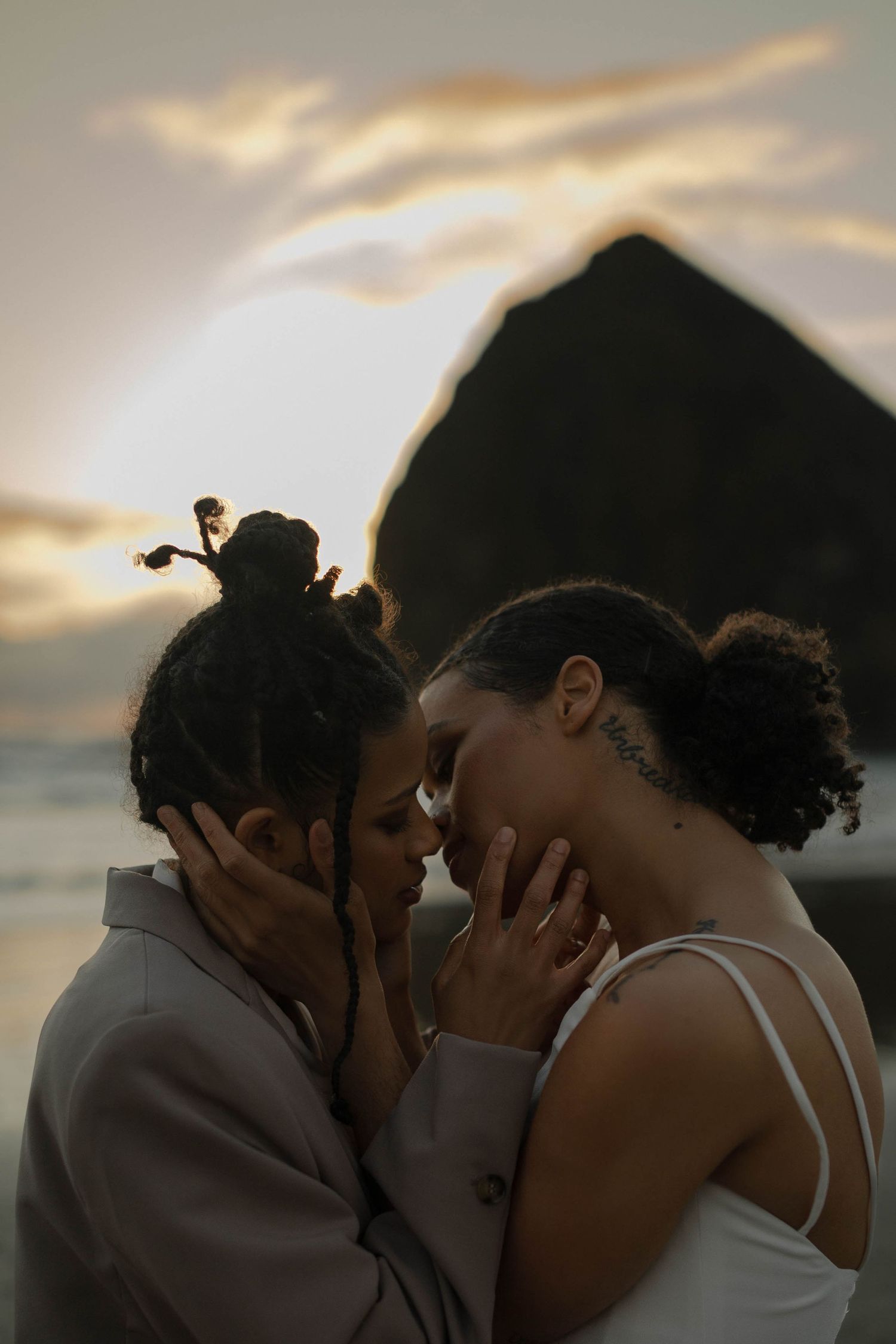 An intimate close-up of a couple sharing a tender moment during their beach wedding at sunset.