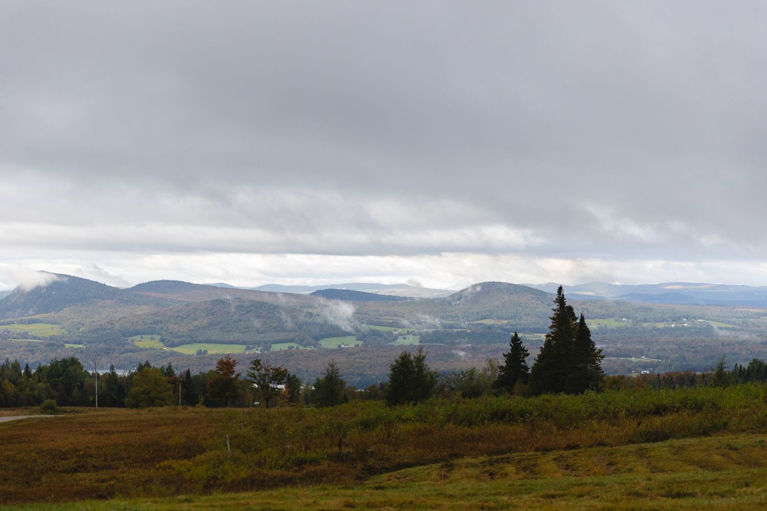 A moody mountain landscape with cloudy skies and rolling hills in autumn.