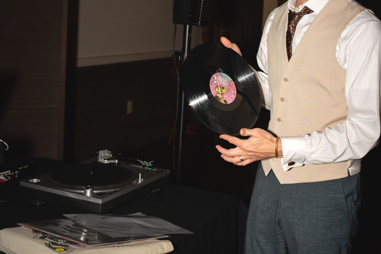 A DJ managing turntables and equipment at a wedding reception.