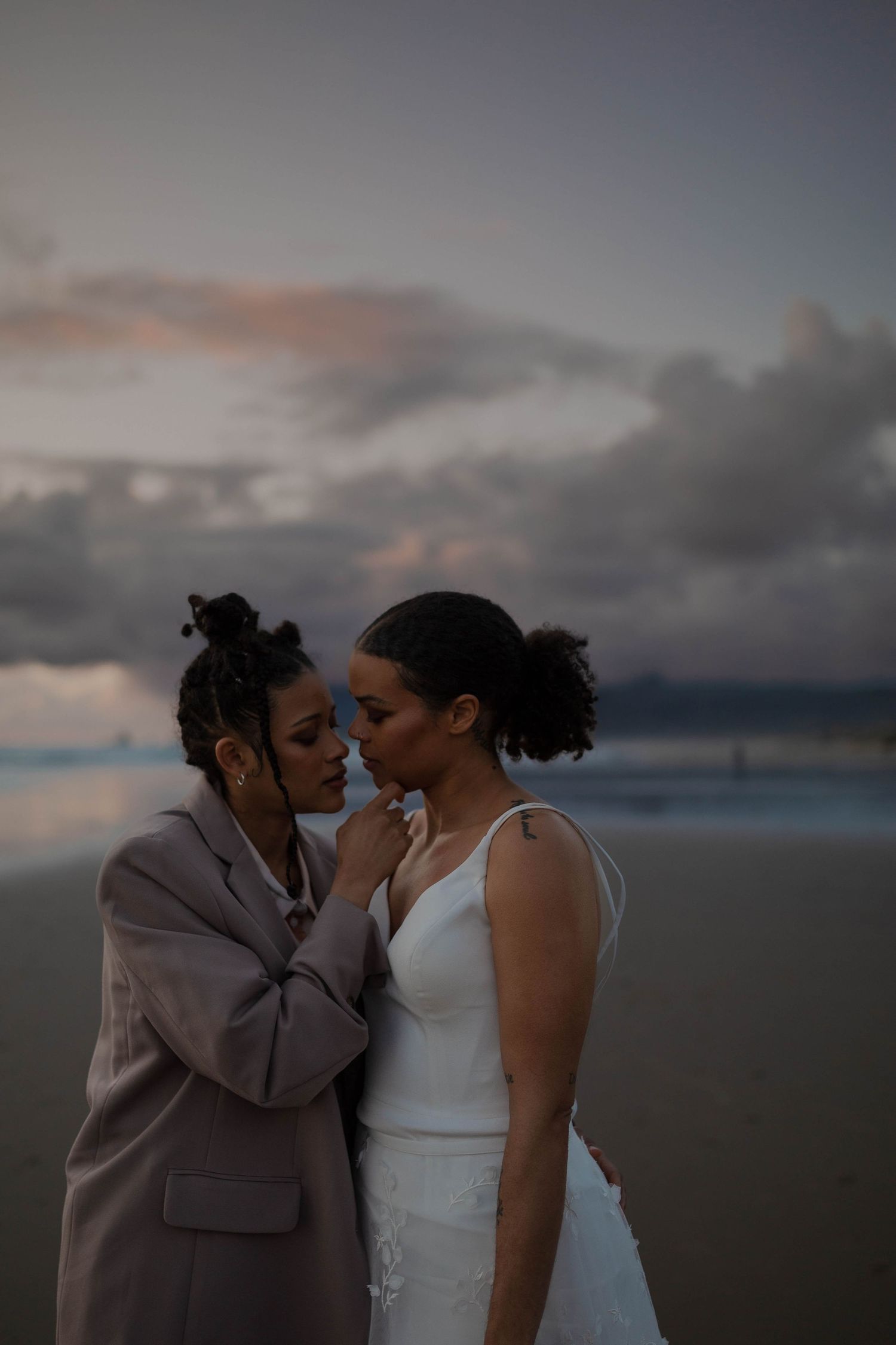 An intimate beachside portrait capturing a tender moment between newlyweds at dusk.