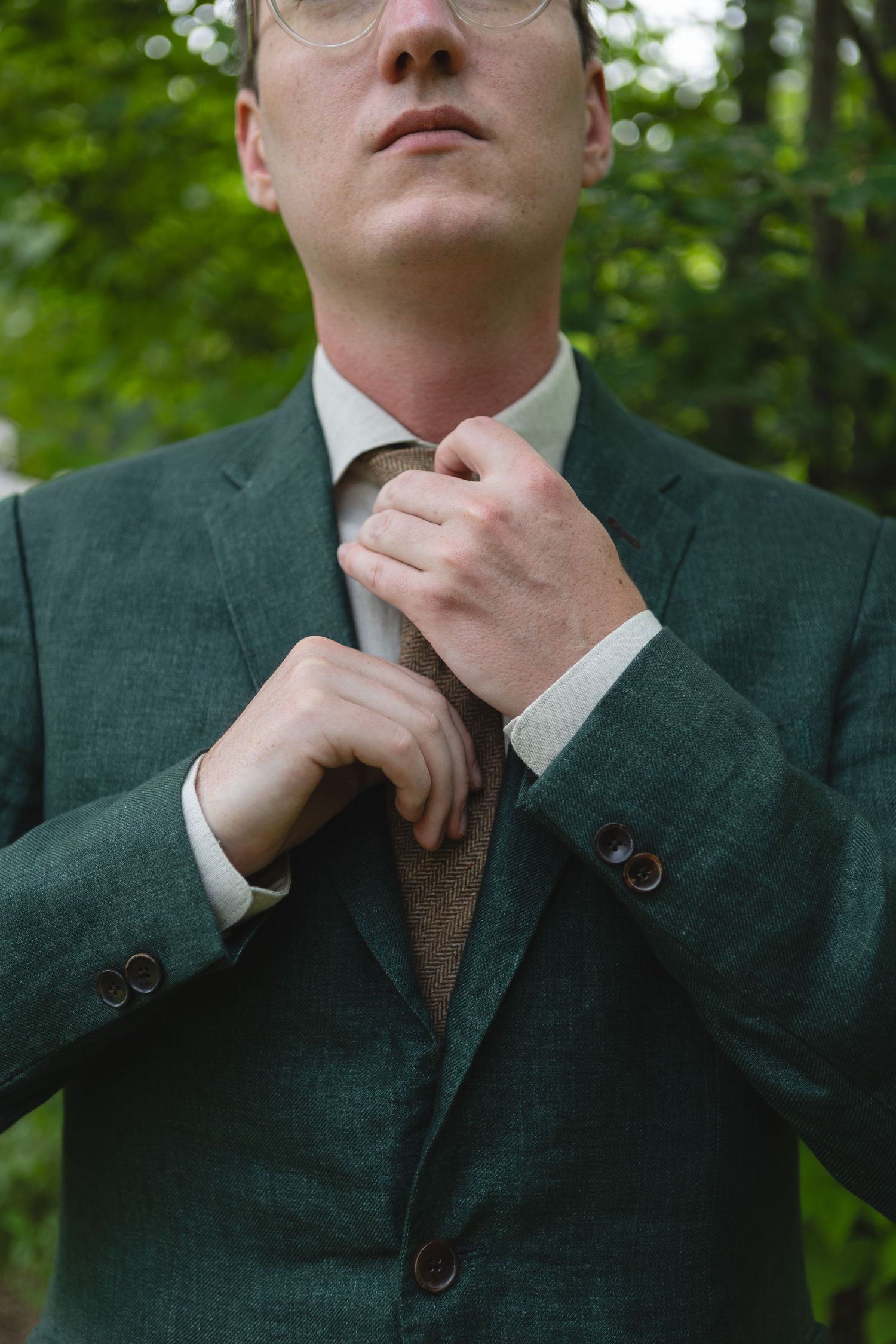 Close up of green suit jacket and tie being adjusted.
