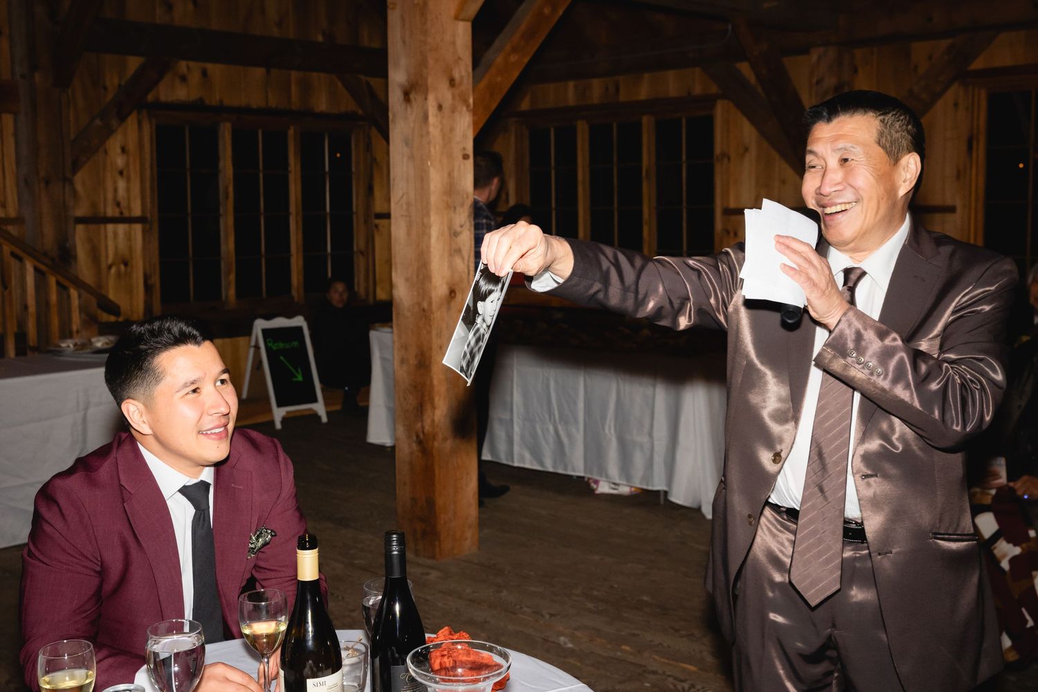 Two guests enjoying a celebratory moment in a rustic wooden barn setting with drinks.