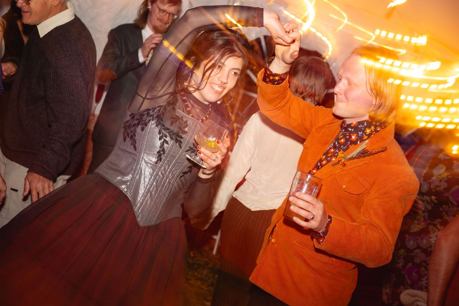 People dancing and socializing at a nightclub with warm orange lighting and blurred motion effects in the background.