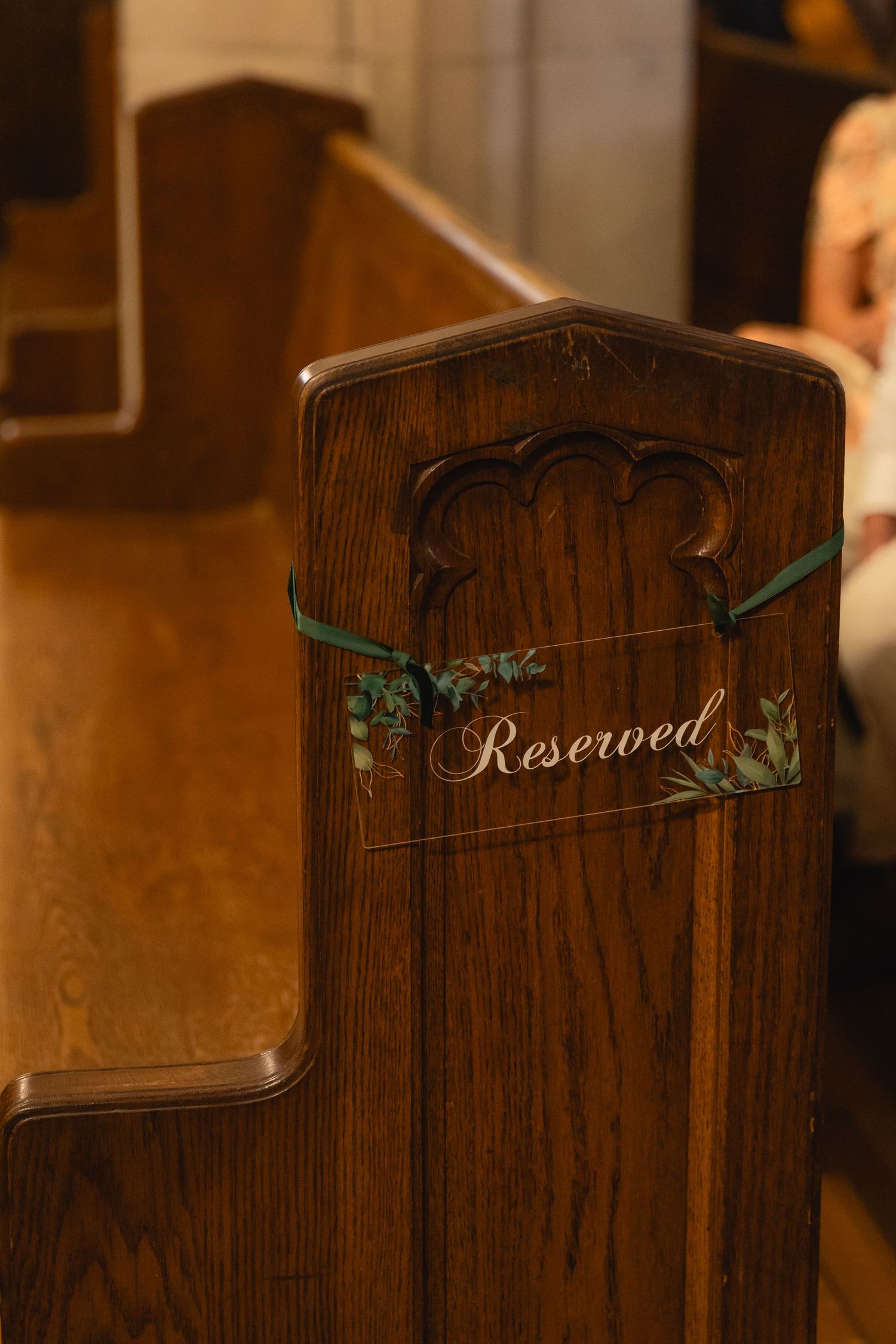 A series of wooden panels showing reserved seating signs with decorative green accents in a dimly lit setting.