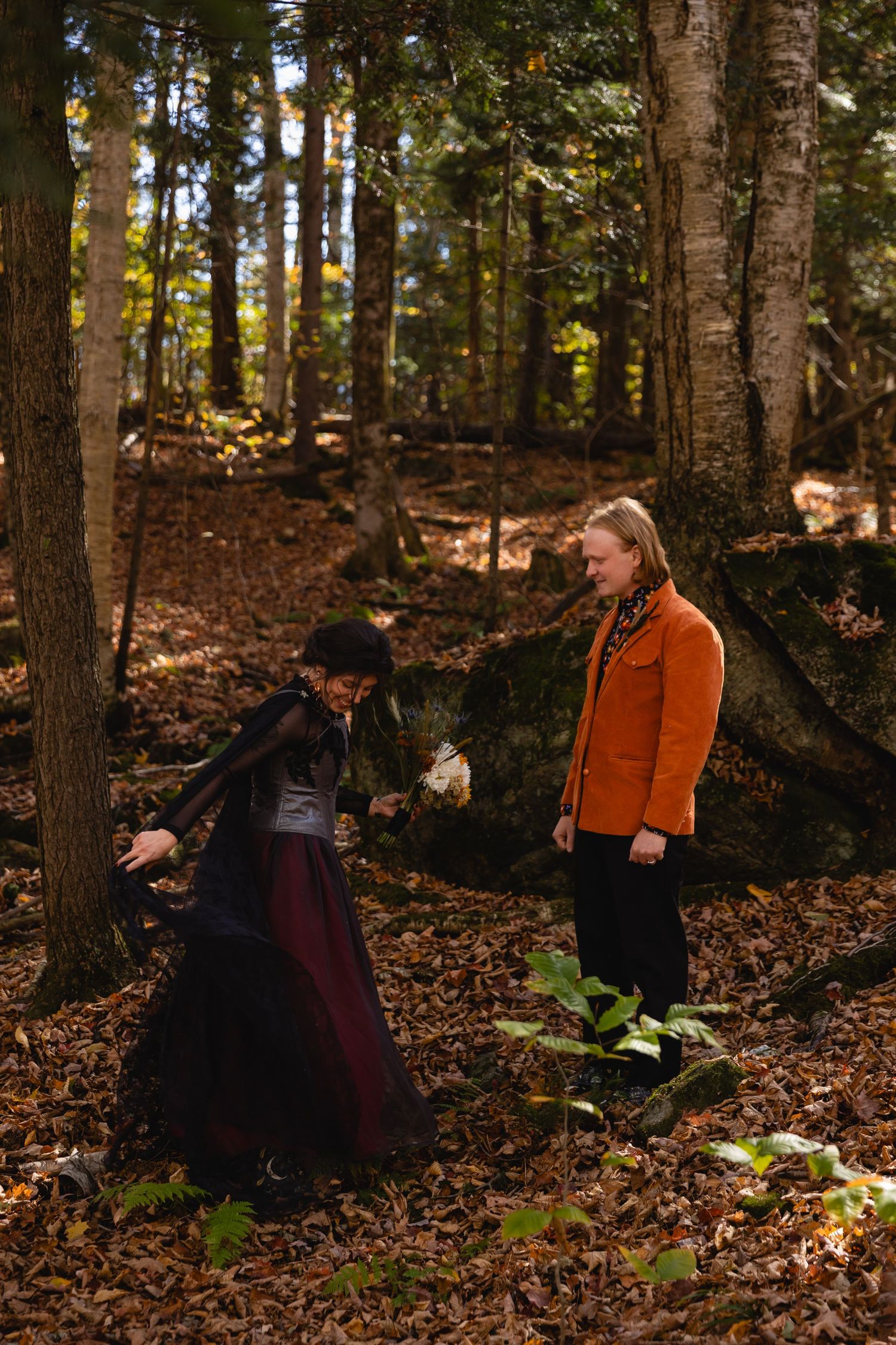 A series of four sequential photos showing people in dark clothing walking through an autumn forest with fallen leaves.
