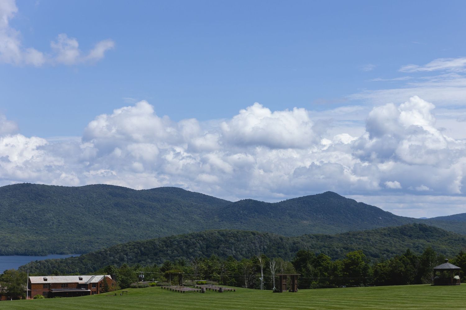 Mountain landscape with green hills and white clouds against a blue sky.