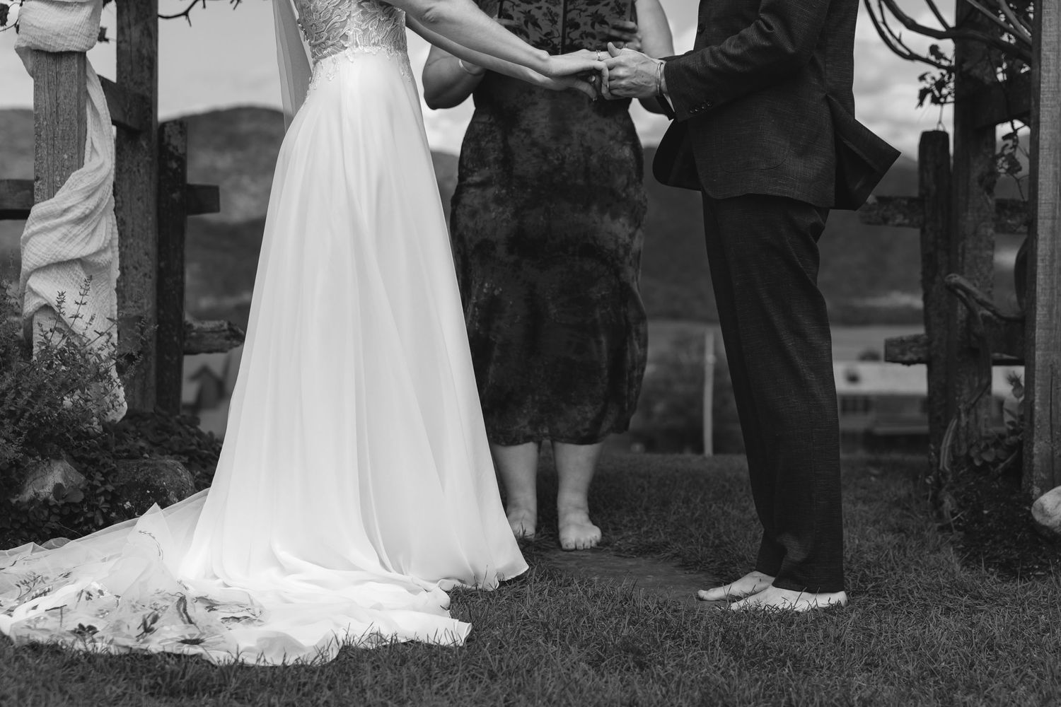 Black and white photo capturing a wedding ceremony moment under a floral arch.