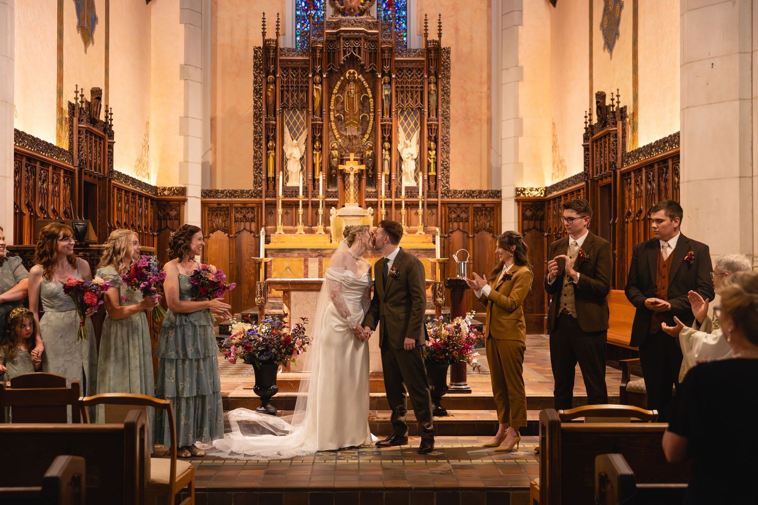 Panoramic view of an ornate Catholic church interior during a wedding ceremony with guests seated in wooden pews.