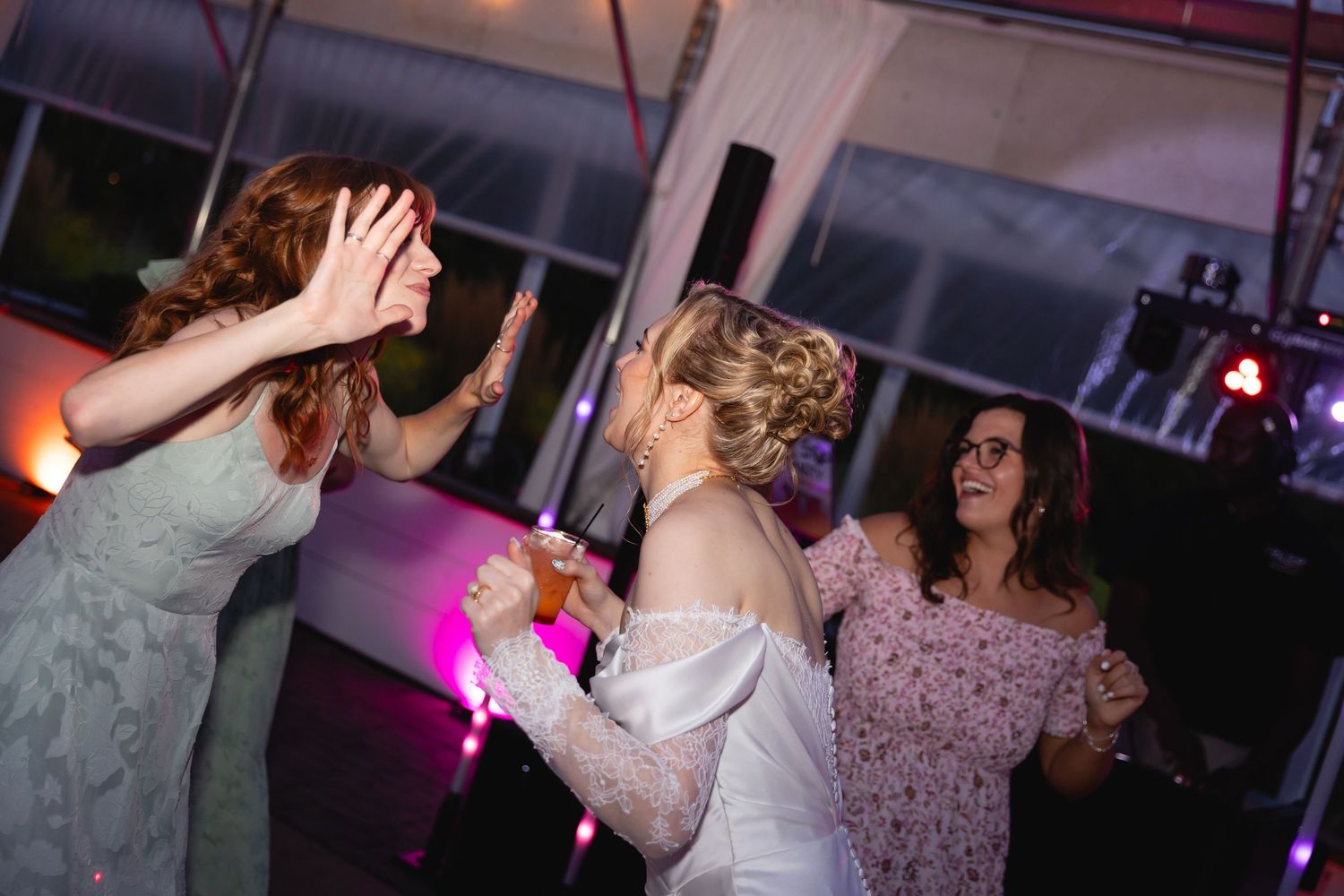 People dancing and celebrating at a party with colorful lighting and festive atmosphere.