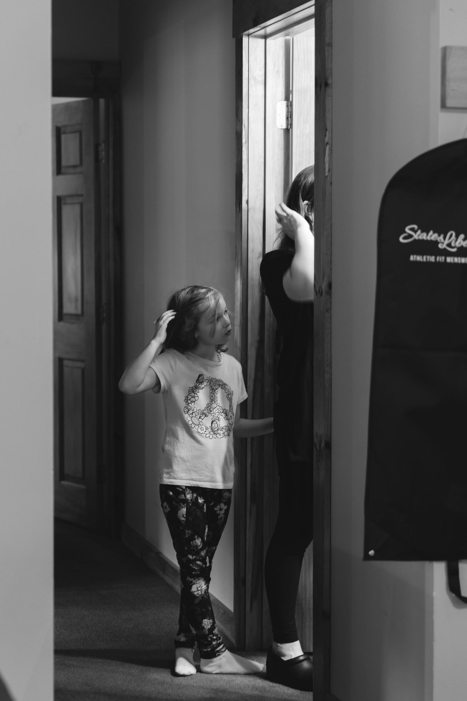Black and white image showing preparation activities in a doorway.