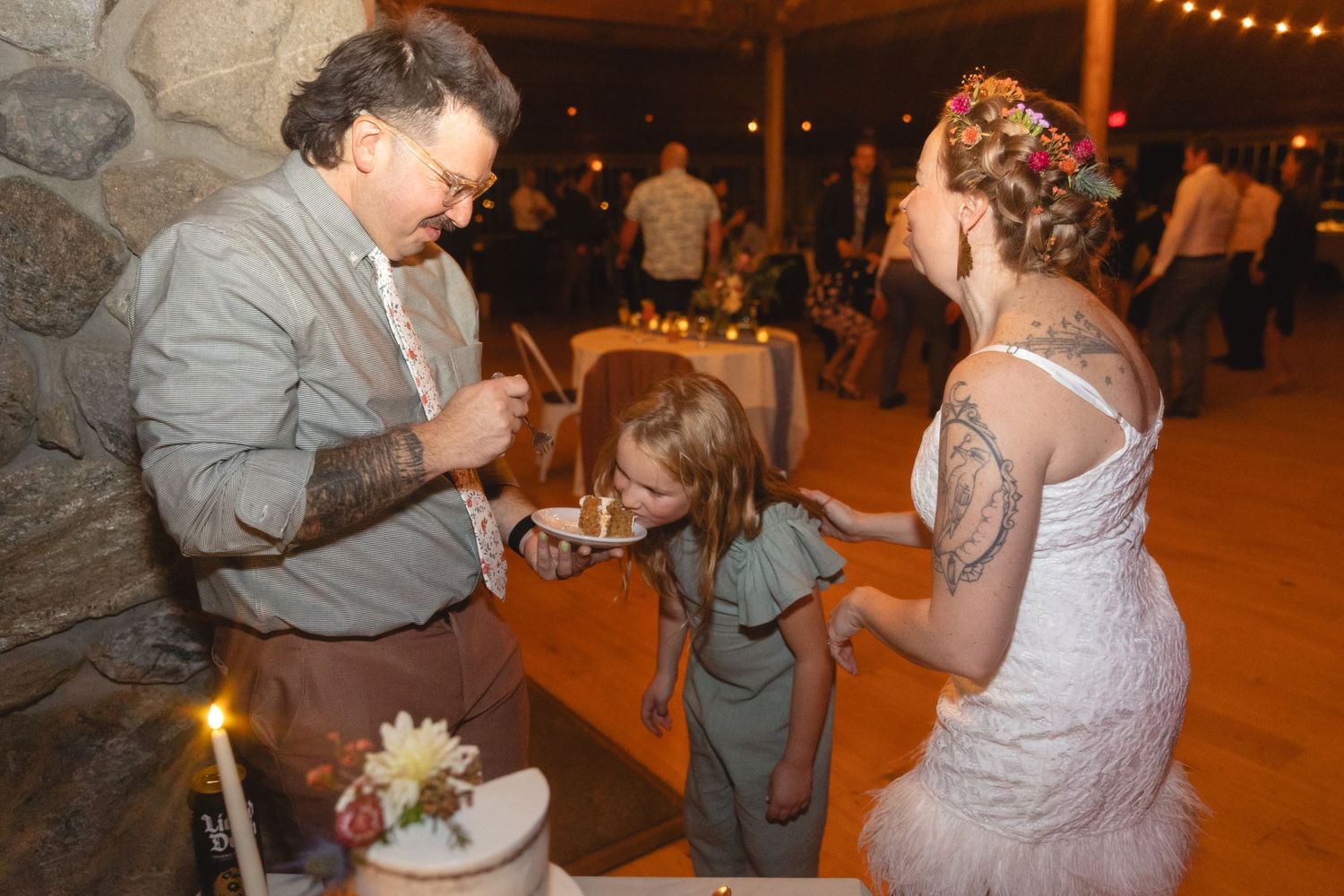 A family feeding each other wedding cake at a warmly lit reception venue.