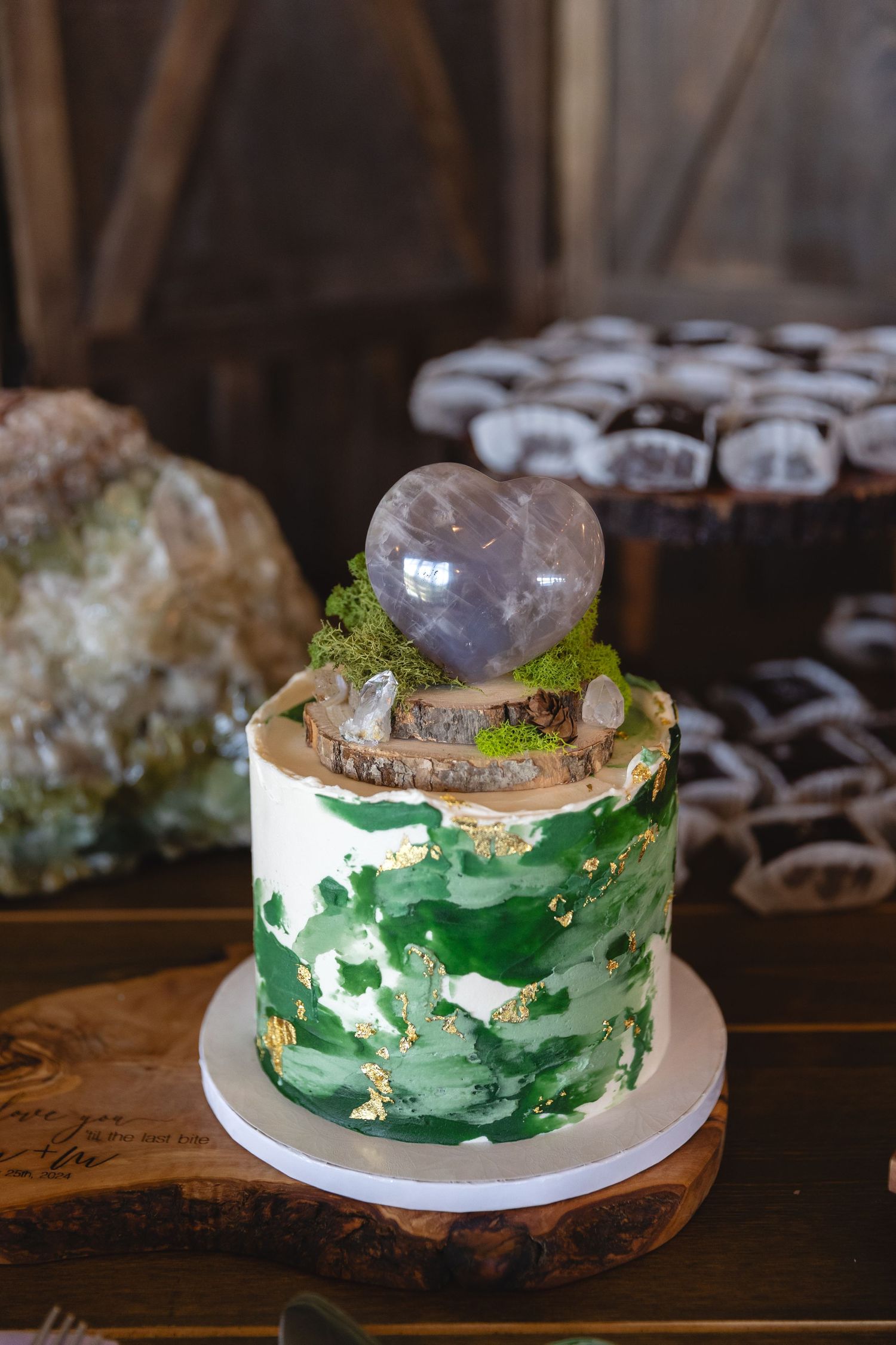 Artistic wedding cake decorated in green watercolor style with crystal geode topper.