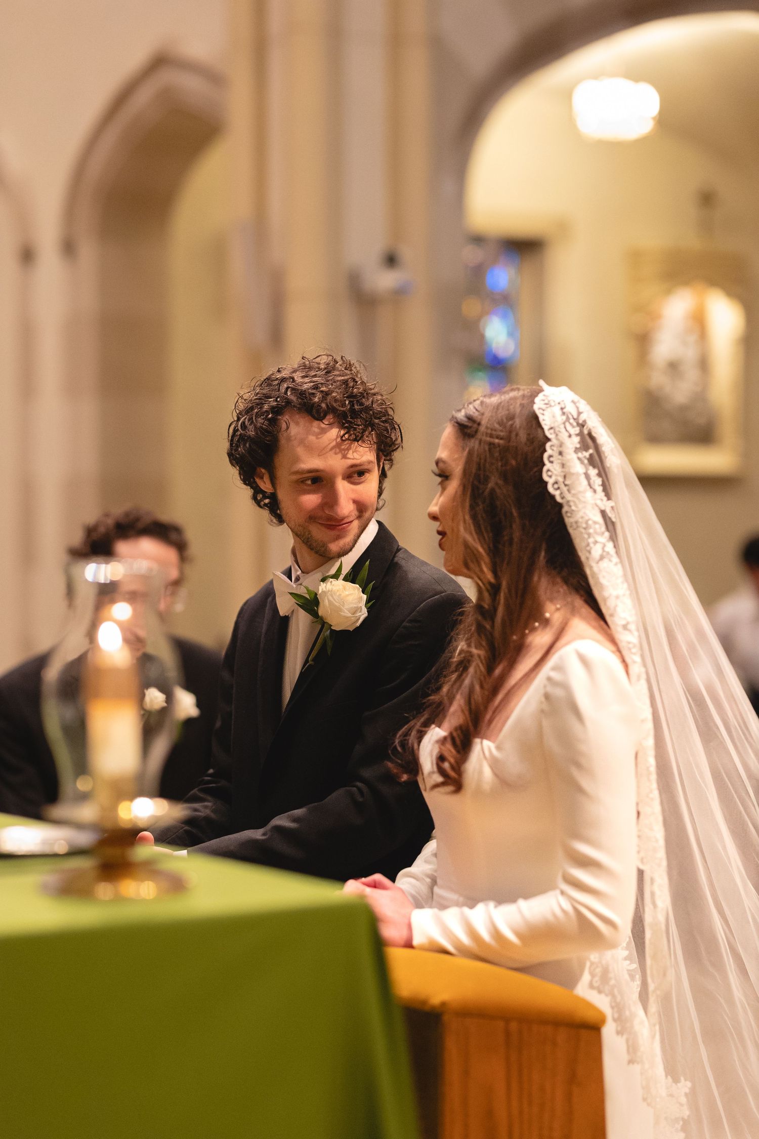 A bride and groom share an intimate moment during their wedding ceremony at the altar in a cathedral.
