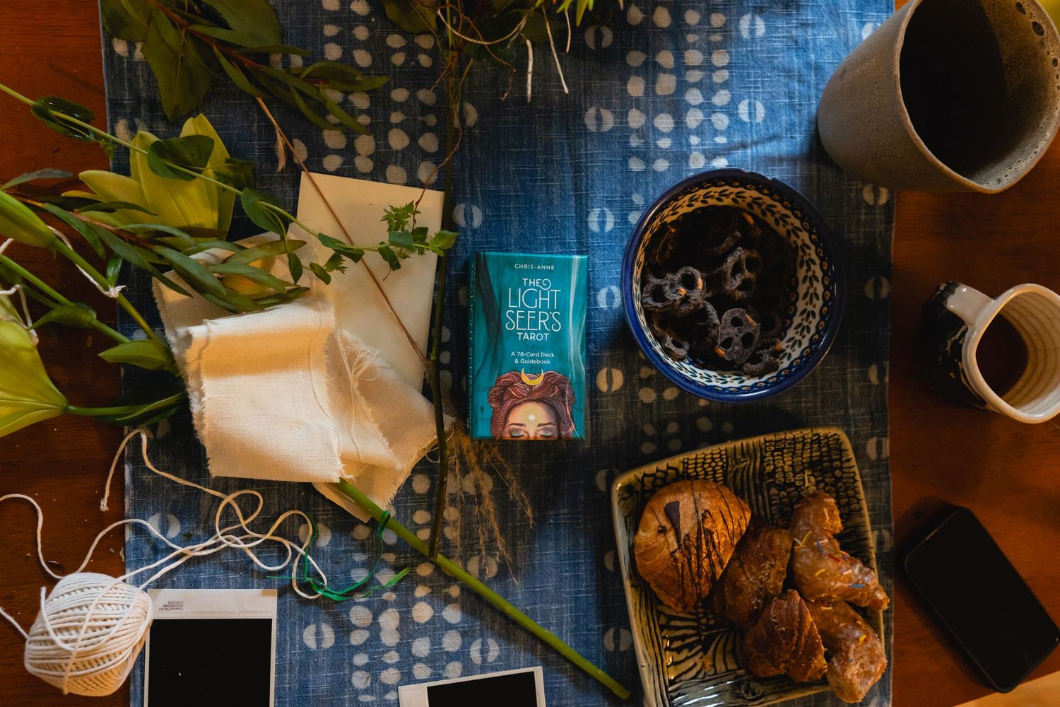 Overhead view of a desk with coffee, tarot cards, and flowers against a blue backdrop with scattered binary numbers.