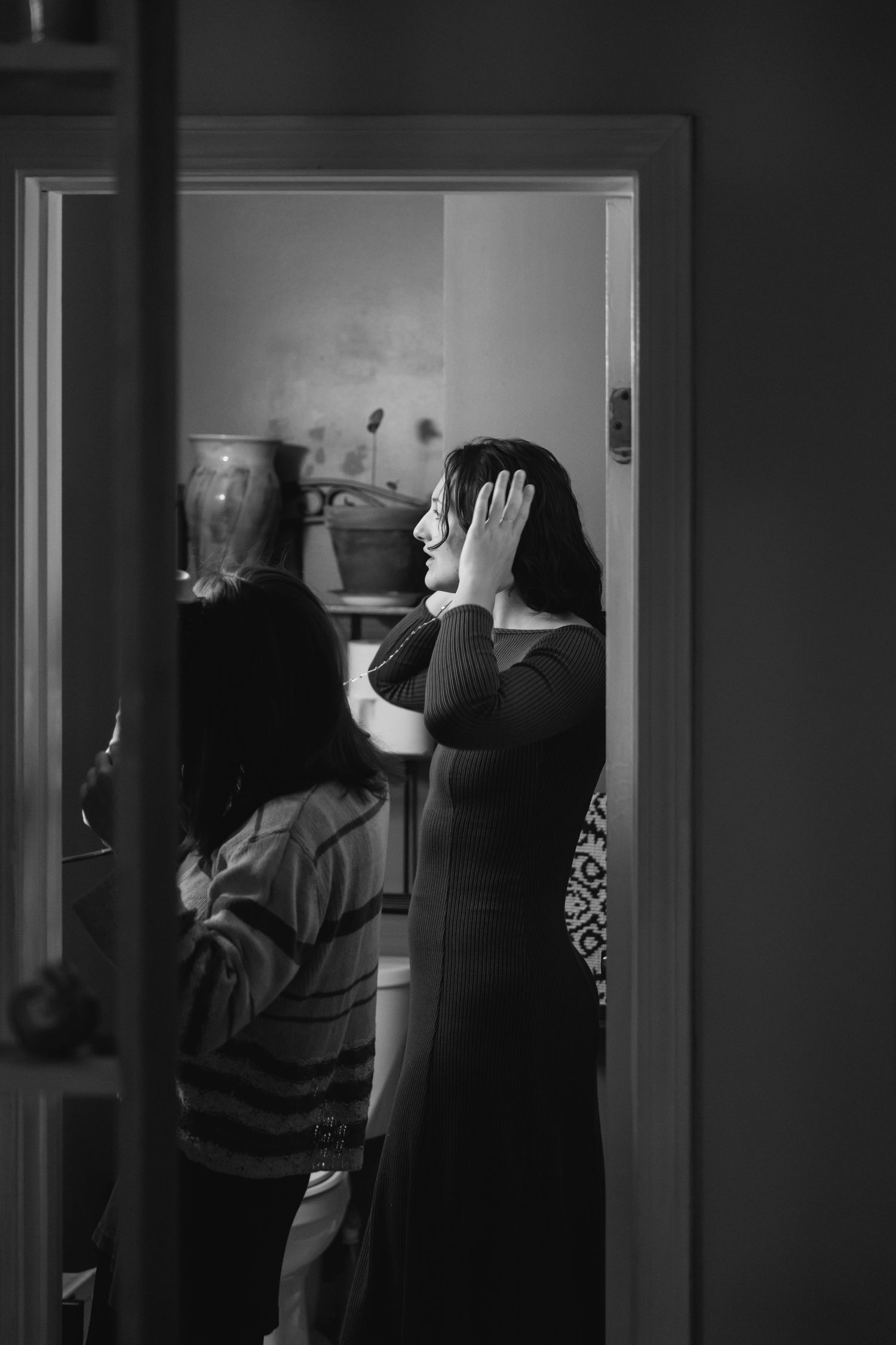 Black and white photo showing a person with hands raised in emotion standing in a doorway.