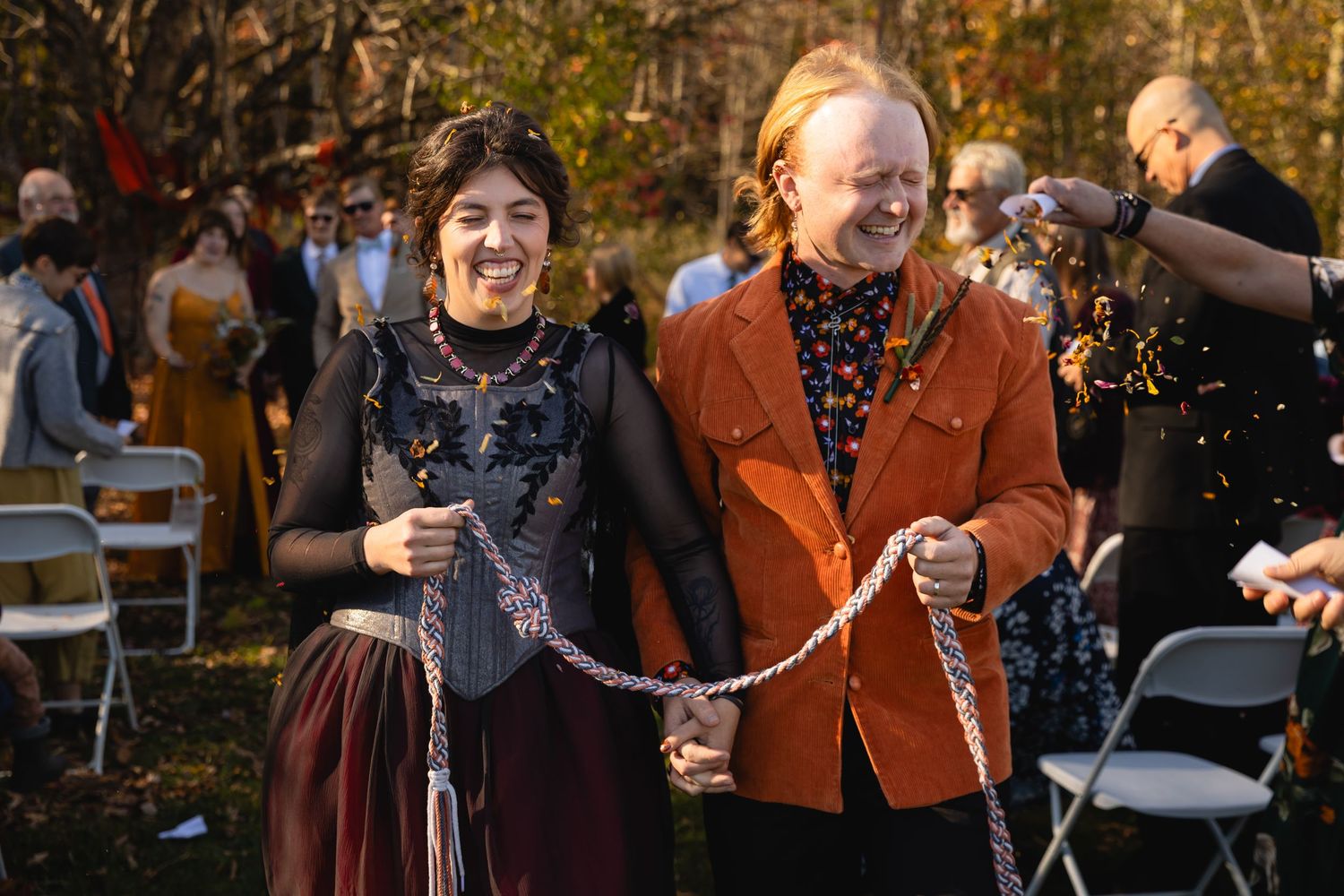 A group of people dancing in a line at an outdoor party with string lights in the background.