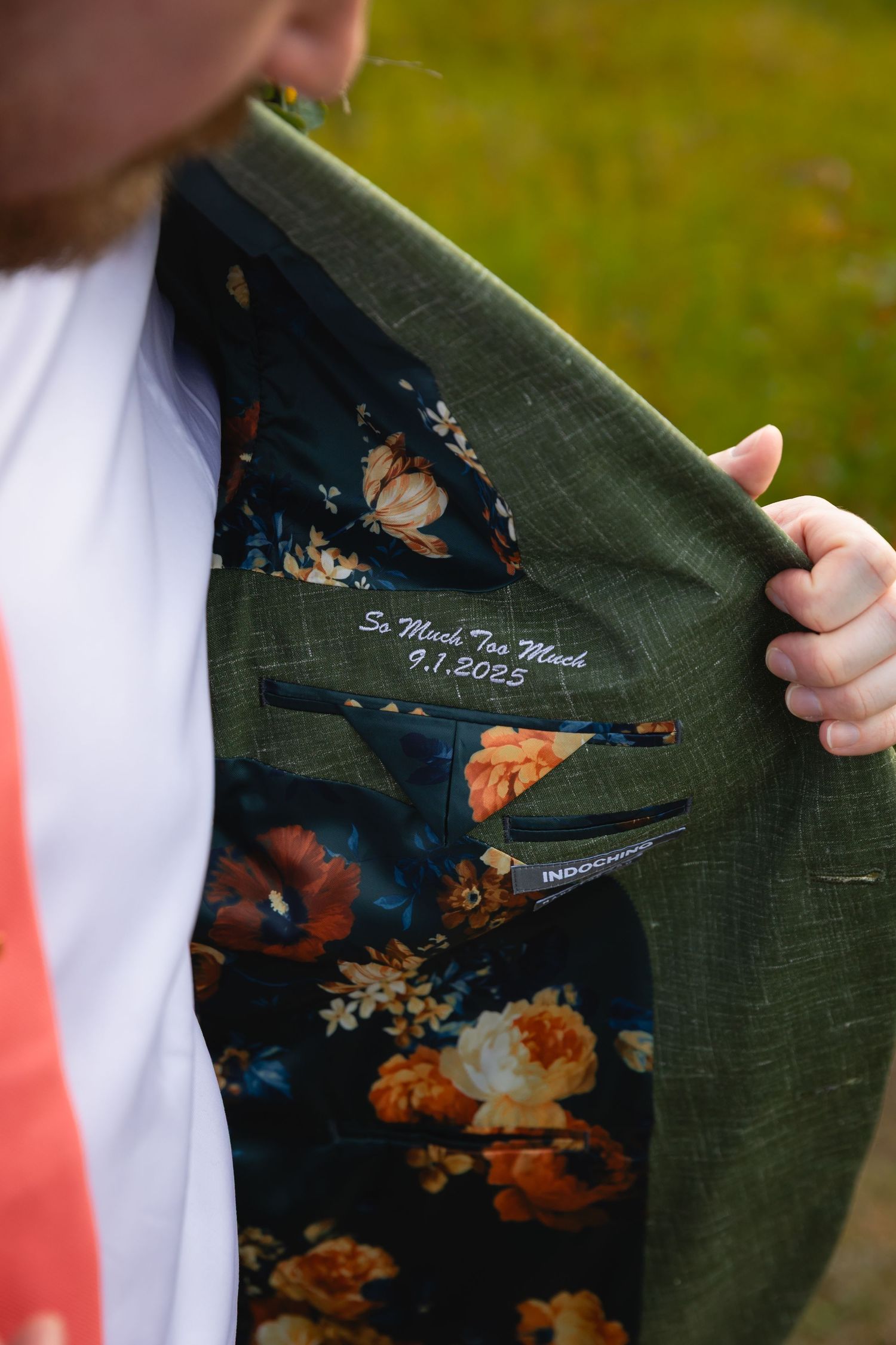 Close-up of suit jacket lining showing embroidered date and floral pattern fabric in navy blue and orange tones.
