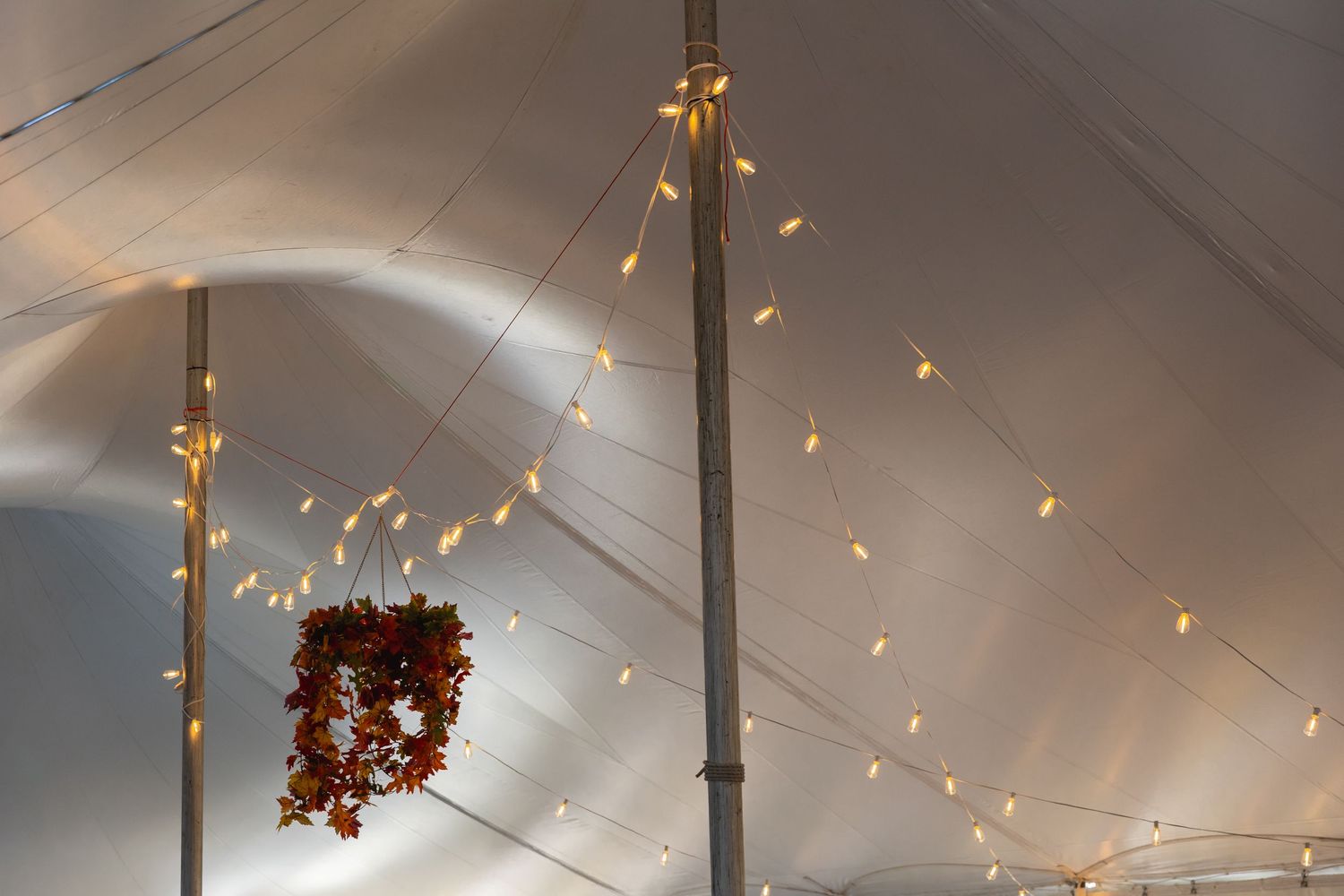 White tent ceiling decorated with warm glowing string lights creating an elegant indoor atmosphere.
