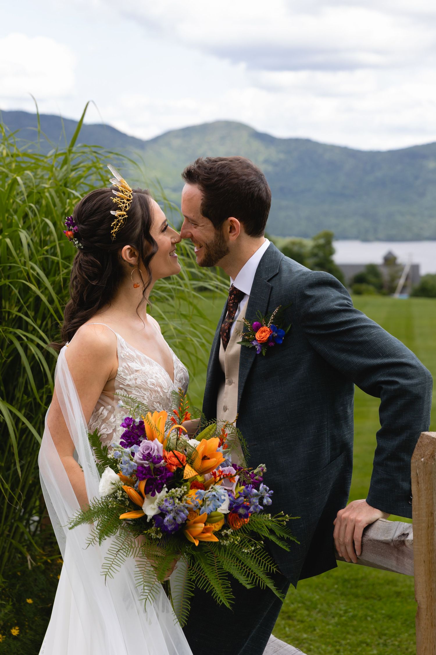 Wedding portrait with mountain lake backdrop and colorful bouquet.