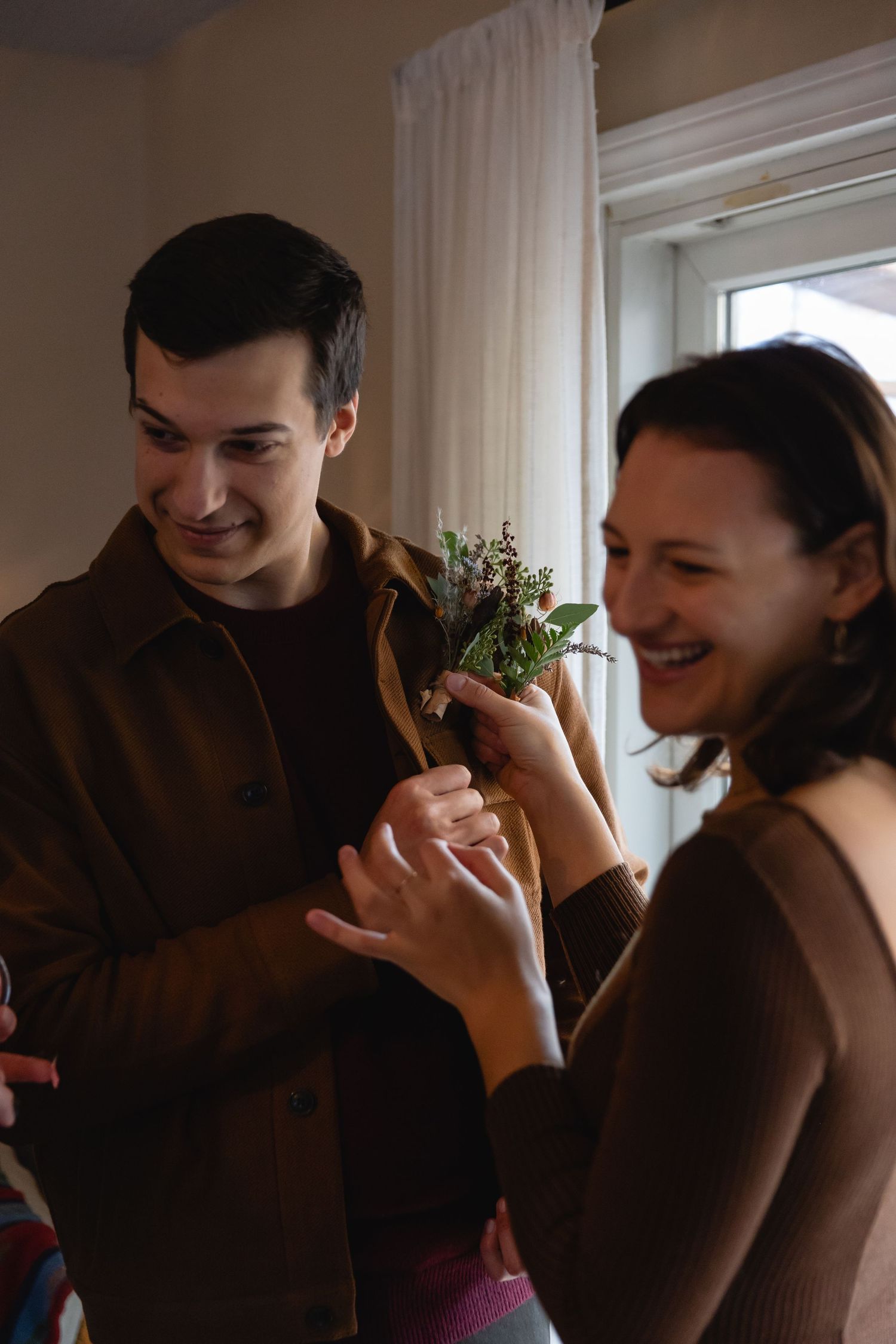 Two people sharing a joyful moment together while looking at some fresh herbs or plants near a window.