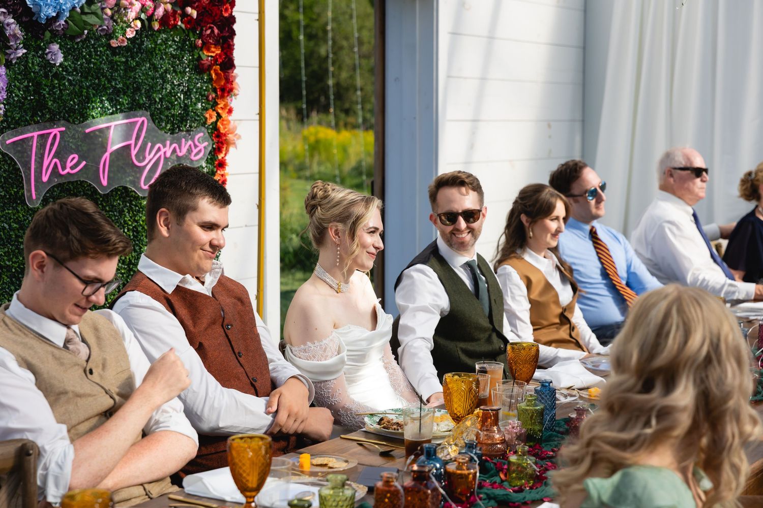 Wedding guests enjoying drinks and conversation at an outdoor reception with autumn floral decorations.