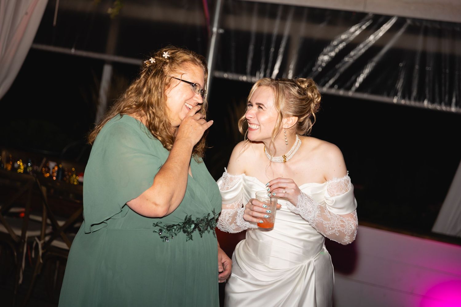 People dancing and celebrating at a party with white outfits and pink lighting in the background.