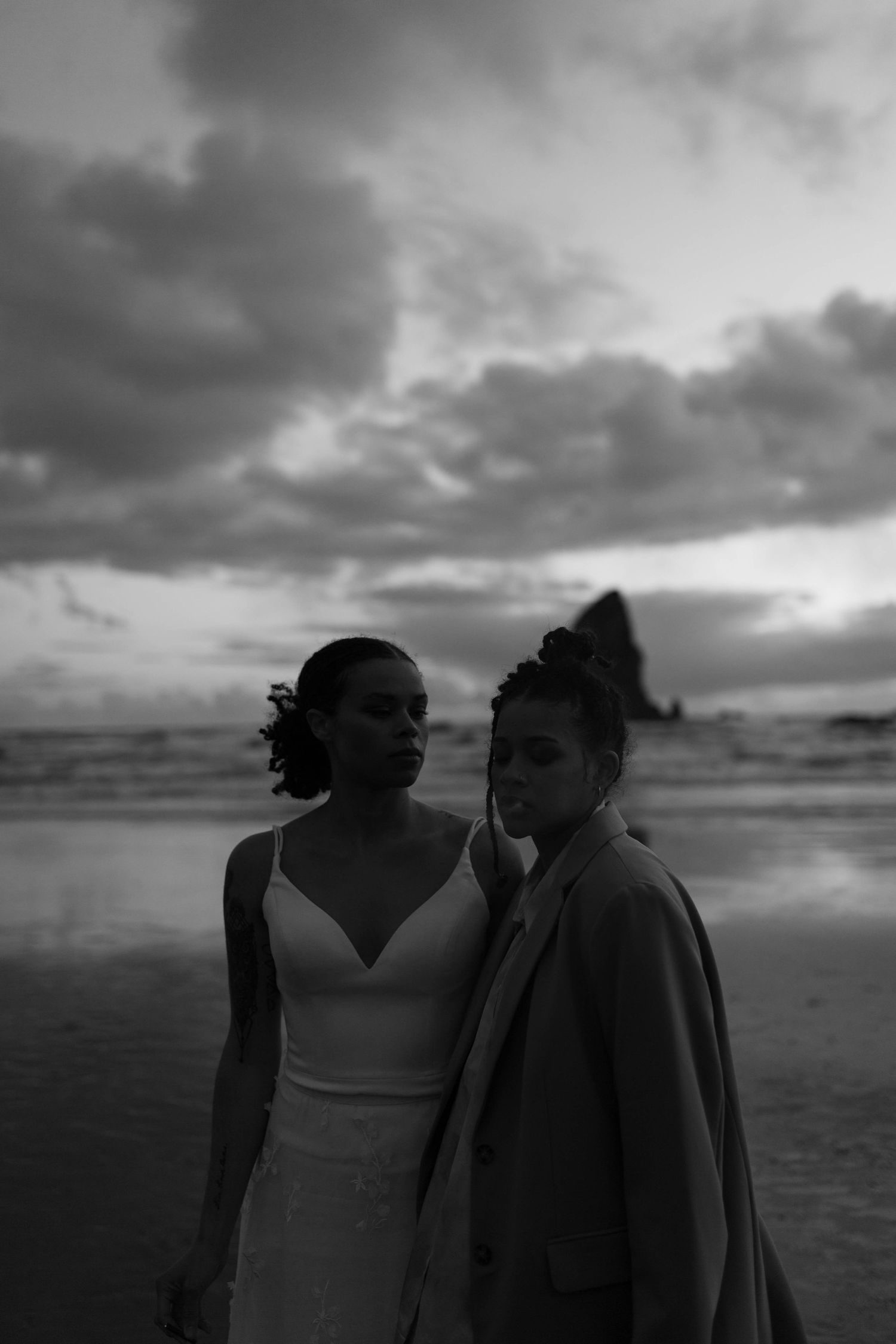 A black and white beach portrait capturing an intimate moment between two people.