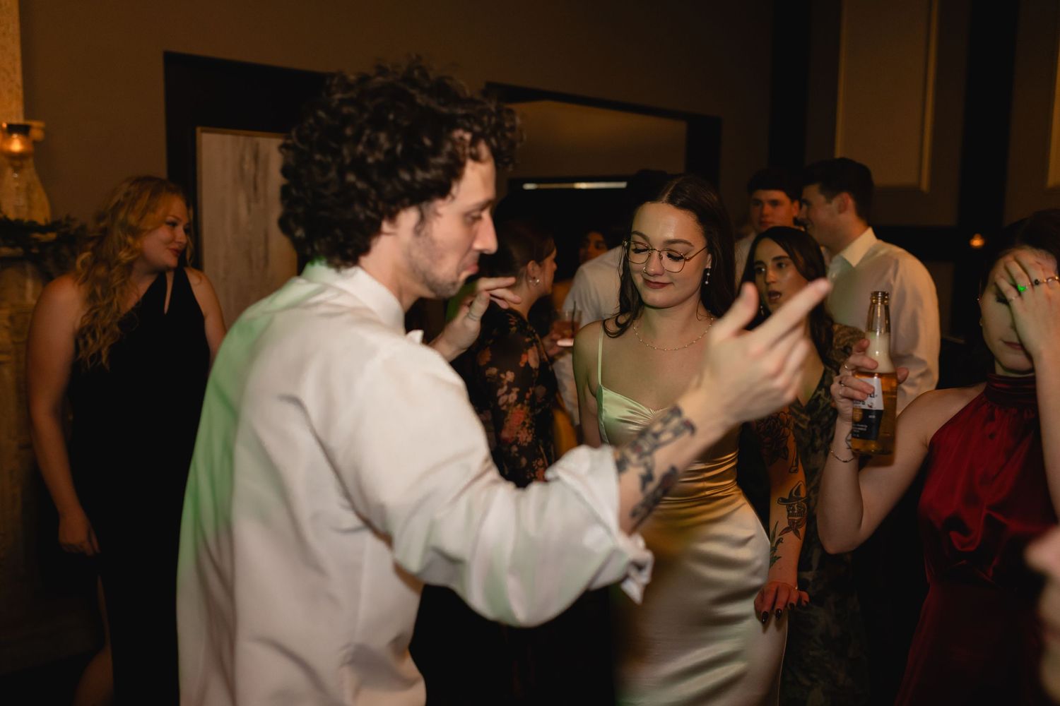 People enthusiastically dancing and interacting at a dimly lit indoor party or celebration event.