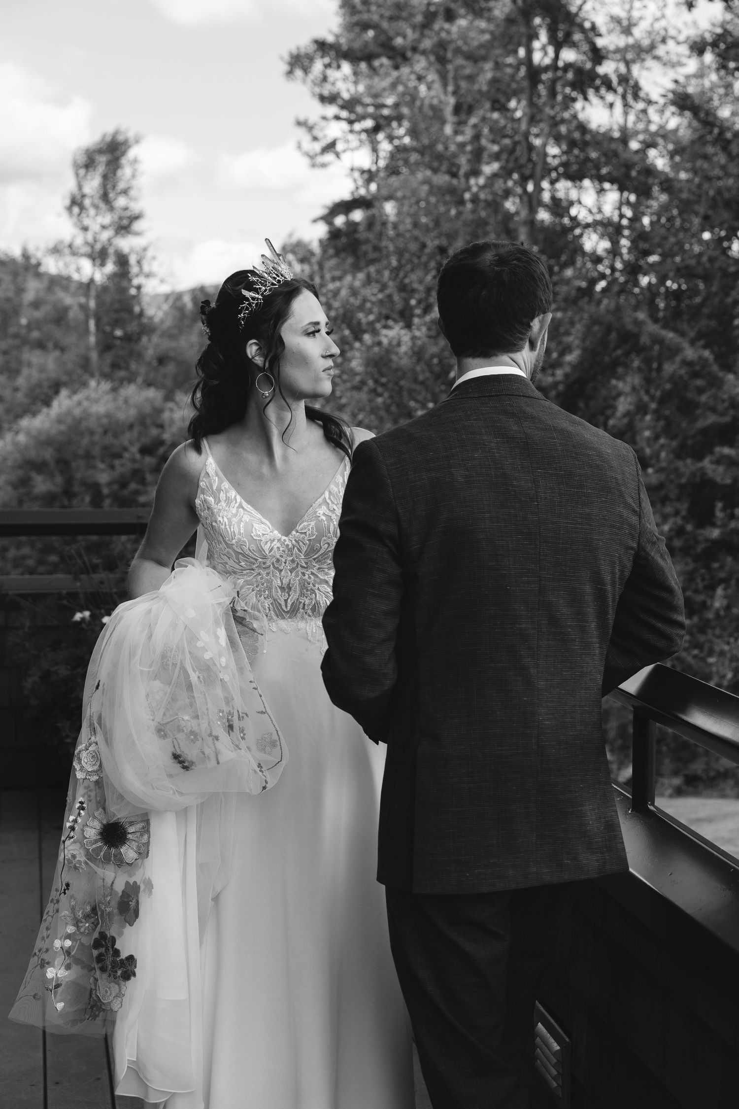 Black and white portrait of a couple on their wedding day standing on a deck.