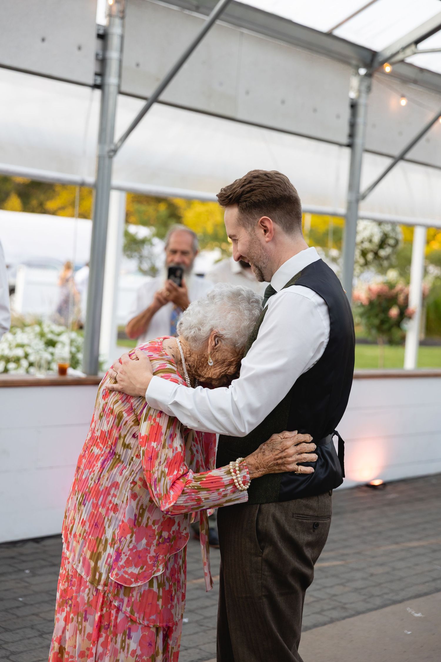 A tender dance sequence showing partners embracing and swaying together at an outdoor event under a white tent.
