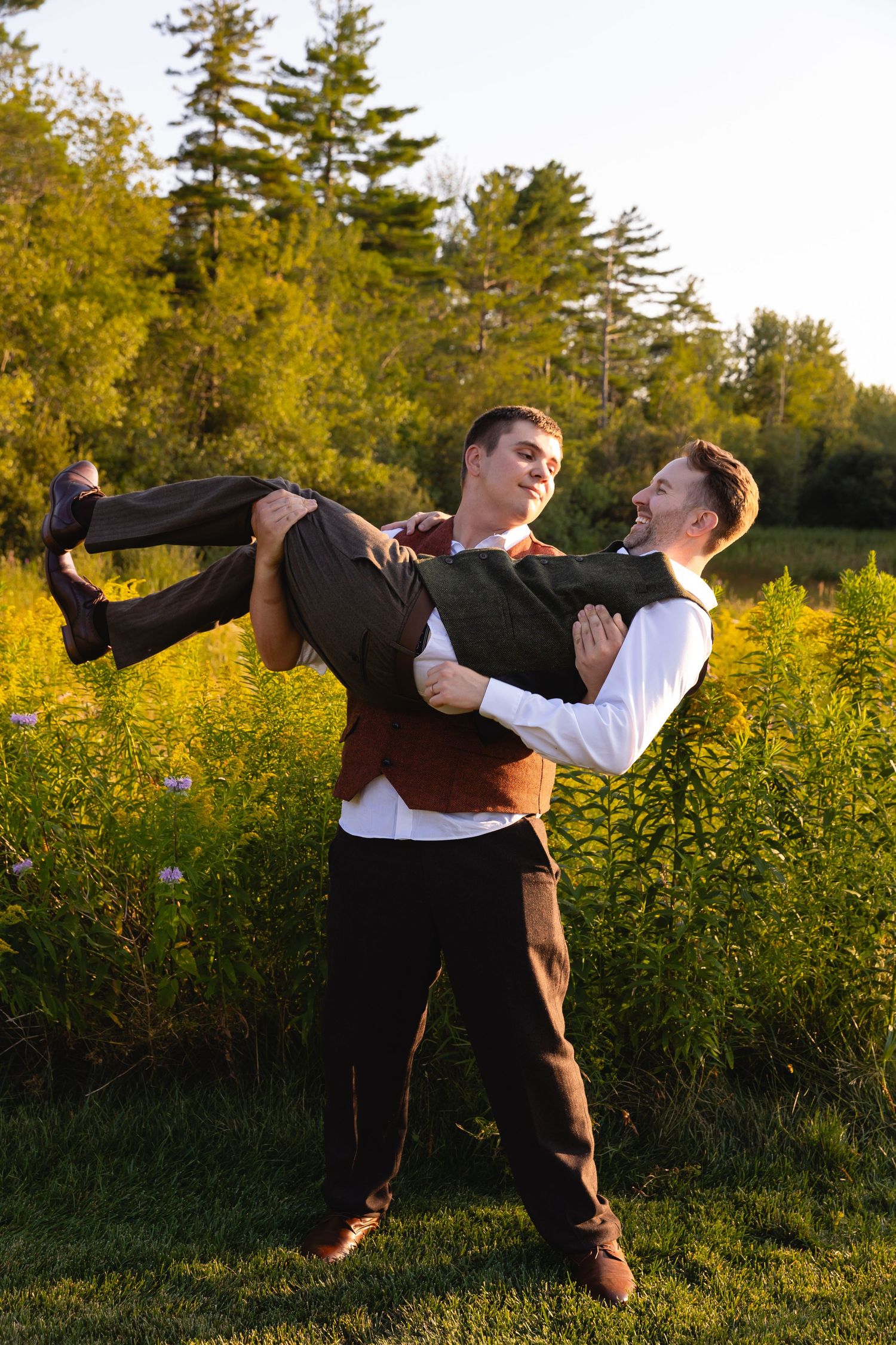 A couple dances together in a field of yellow wildflowers at sunset, performing a dramatic dip move.