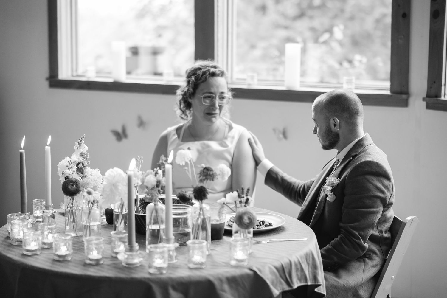 A couple shares an intimate moment at their wedding reception table decorated with elegant candles and floral centerpieces.