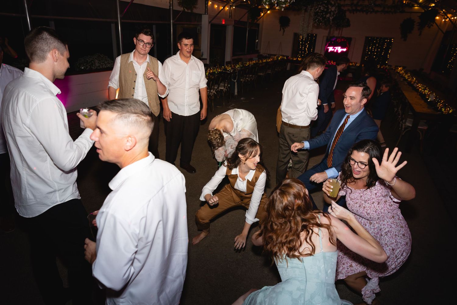 People dancing and celebrating together at a dimly lit evening party or reception.